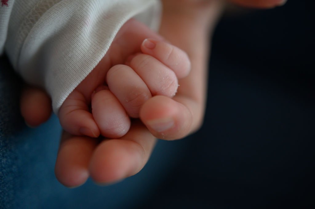 La mano de un recién nacido de dos semanas sobre la mano de su madre. | Foto de Sebastian Gollnow a través de Getty Images