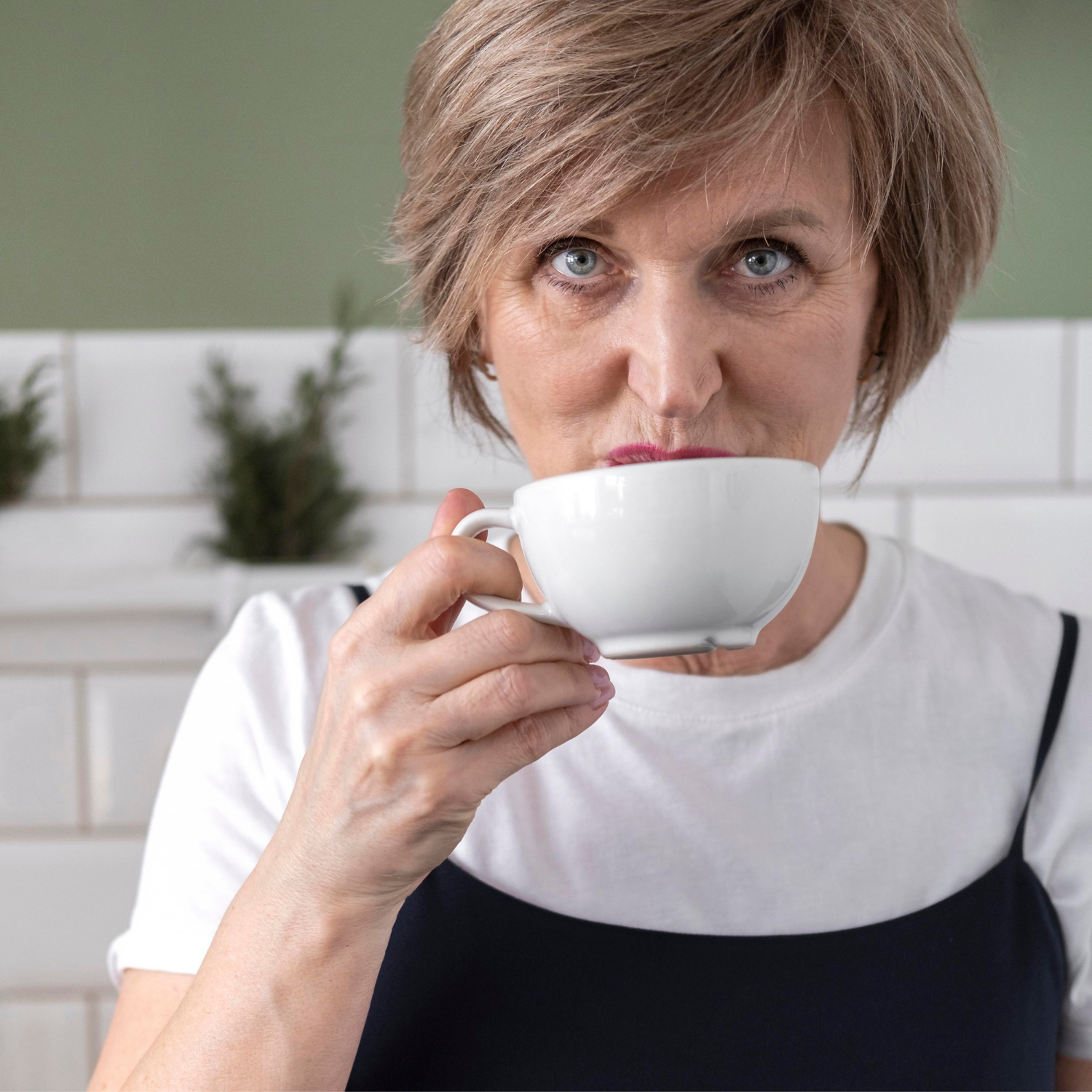 Una mujer mayor sonriente sosteniendo una taza de cerámica | Fuente: Freepik