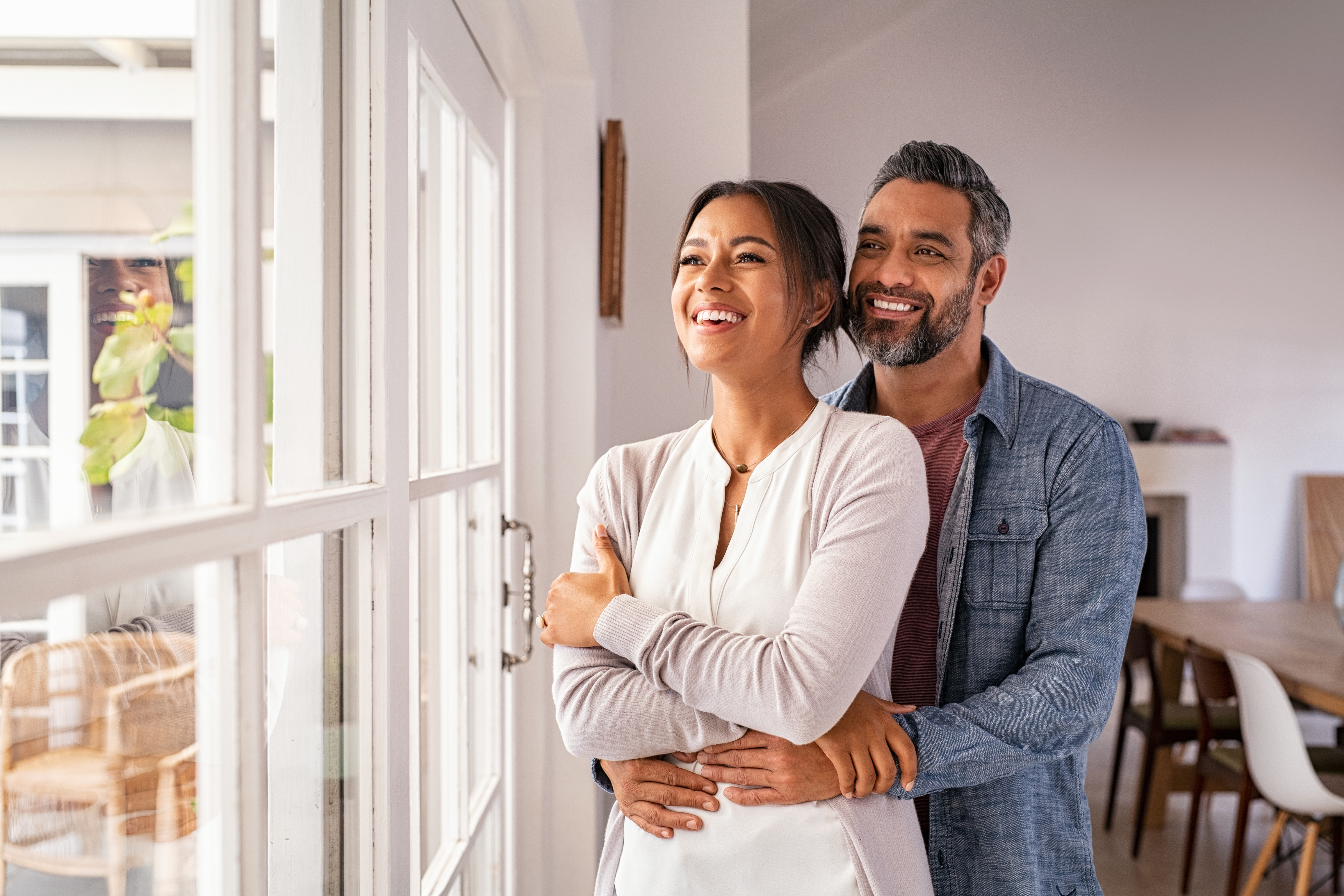 Una pareja feliz sonriendo y mirando por una ventana | Fuente: Shutterstock