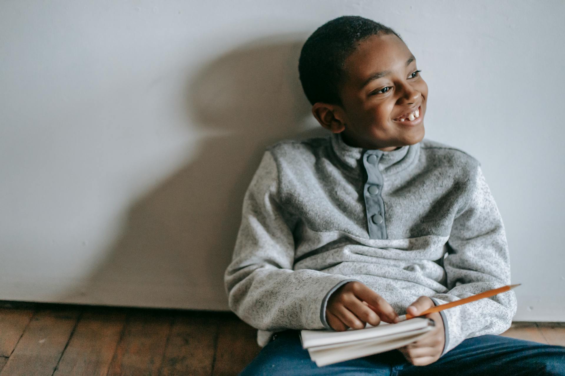 Un niño sentado en el suelo y riéndose | Fuente: Pexels