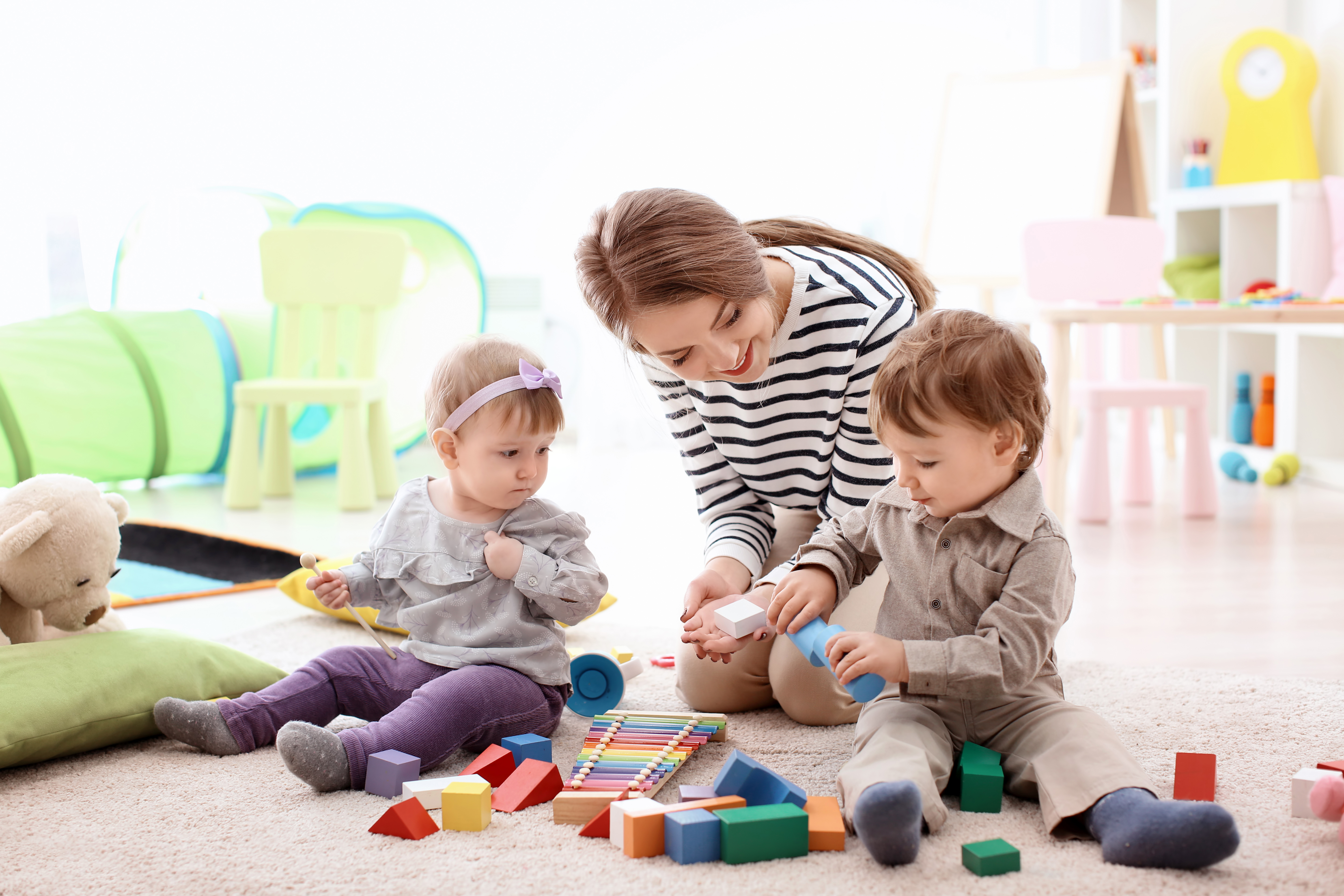Una joven ayuda a dos niños pequeños durante el recreo | Foto: Shutterstock