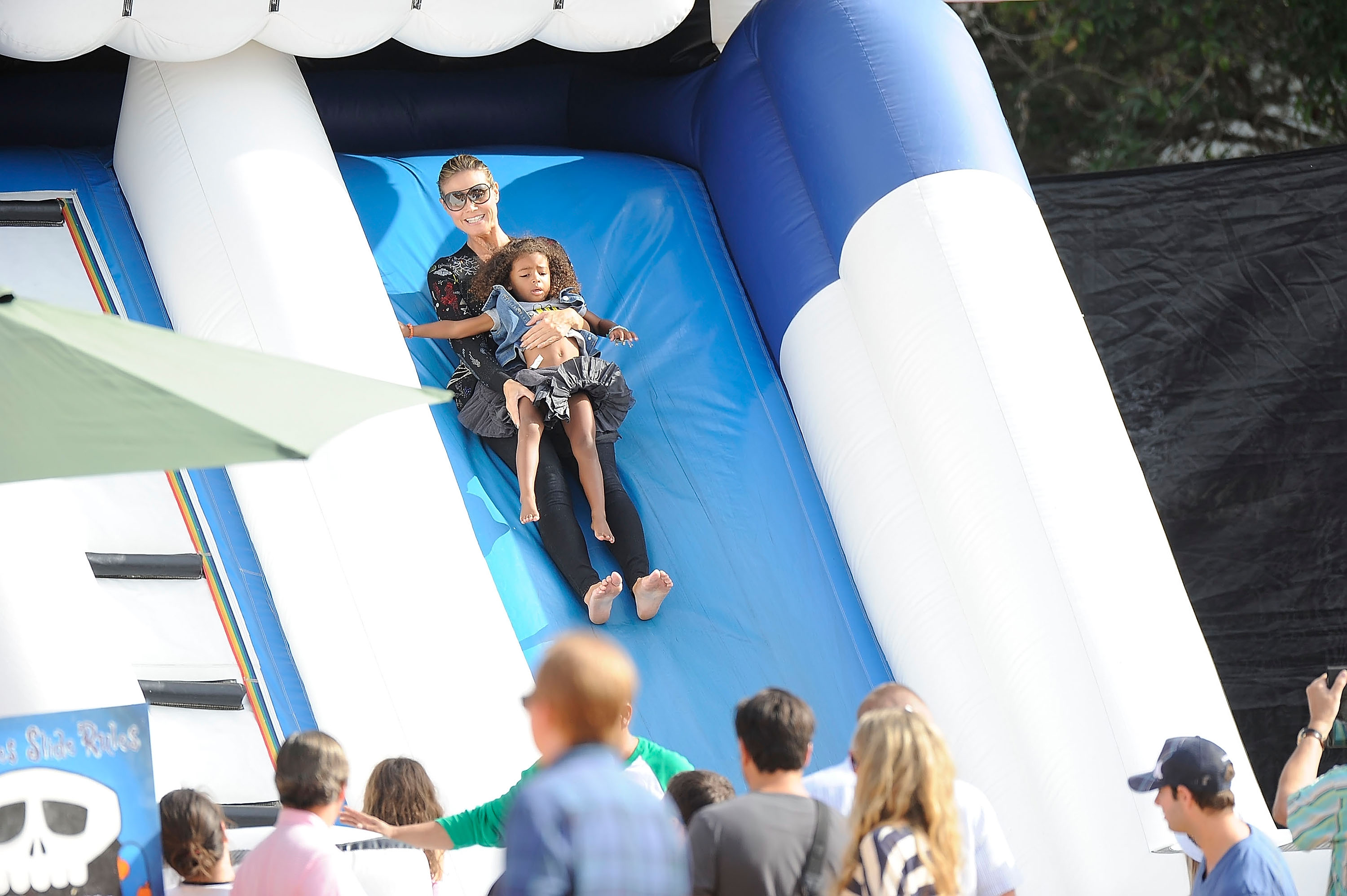 Heidi Klum vista bajando por el tobogán de un castillo saltarín con su hija Lou Samuel en el huerto de calabazas Mr. Bones el 6 de octubre de 2012, en Los Ángeles, California | Fuente: Getty Images