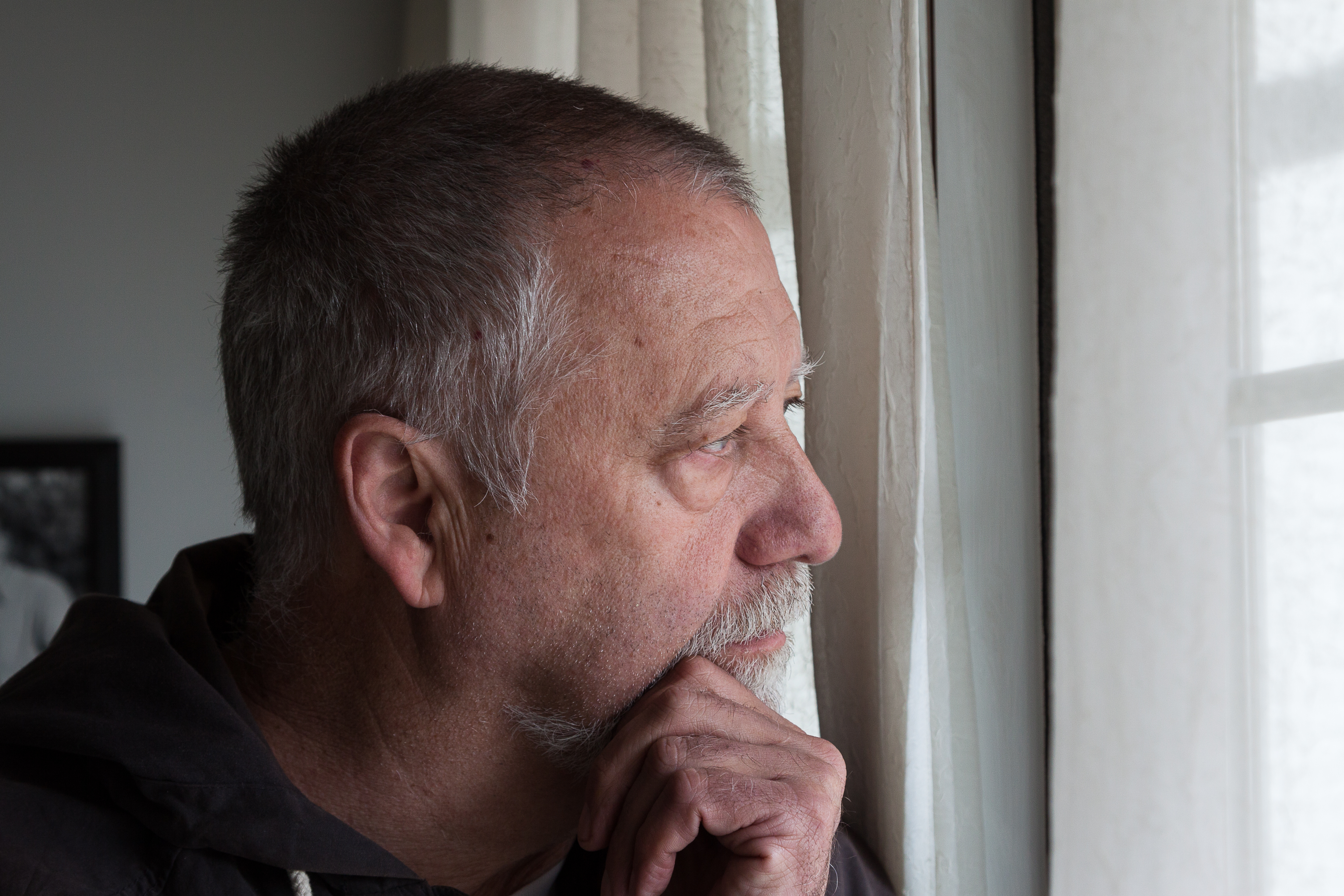 Hombre triste se queda cerca de la ventana | Fuente: Shutterstock.com