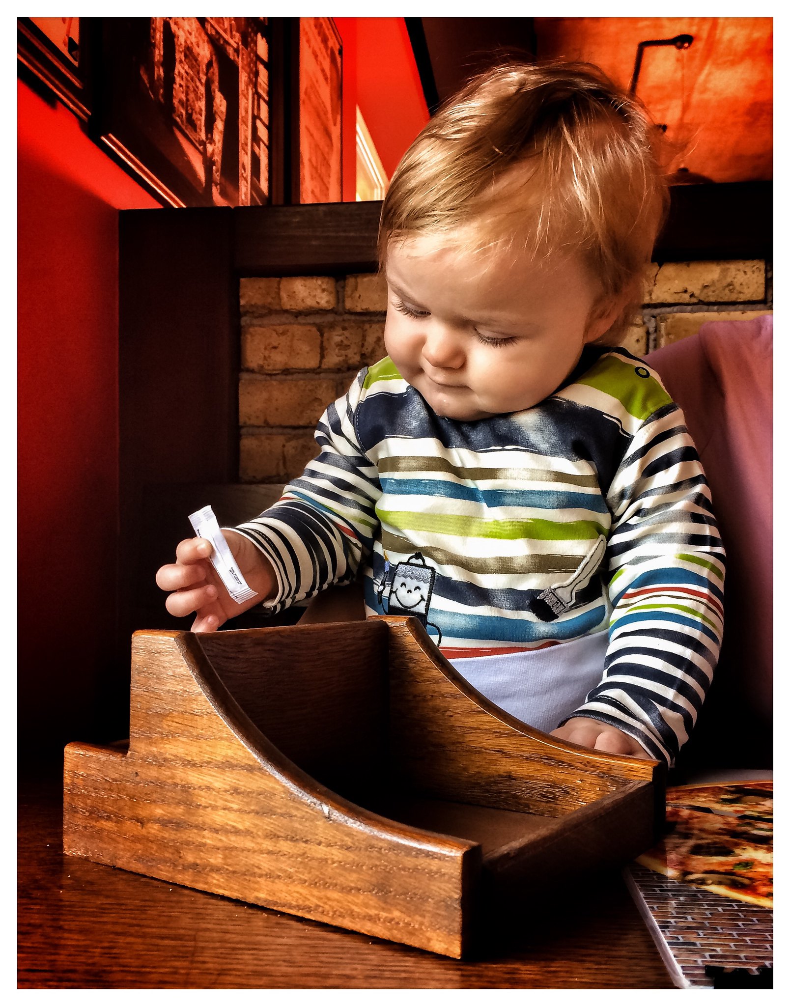 Un niño jugando con un sobre de azúcar en un restaurante | Foto: Flickr
