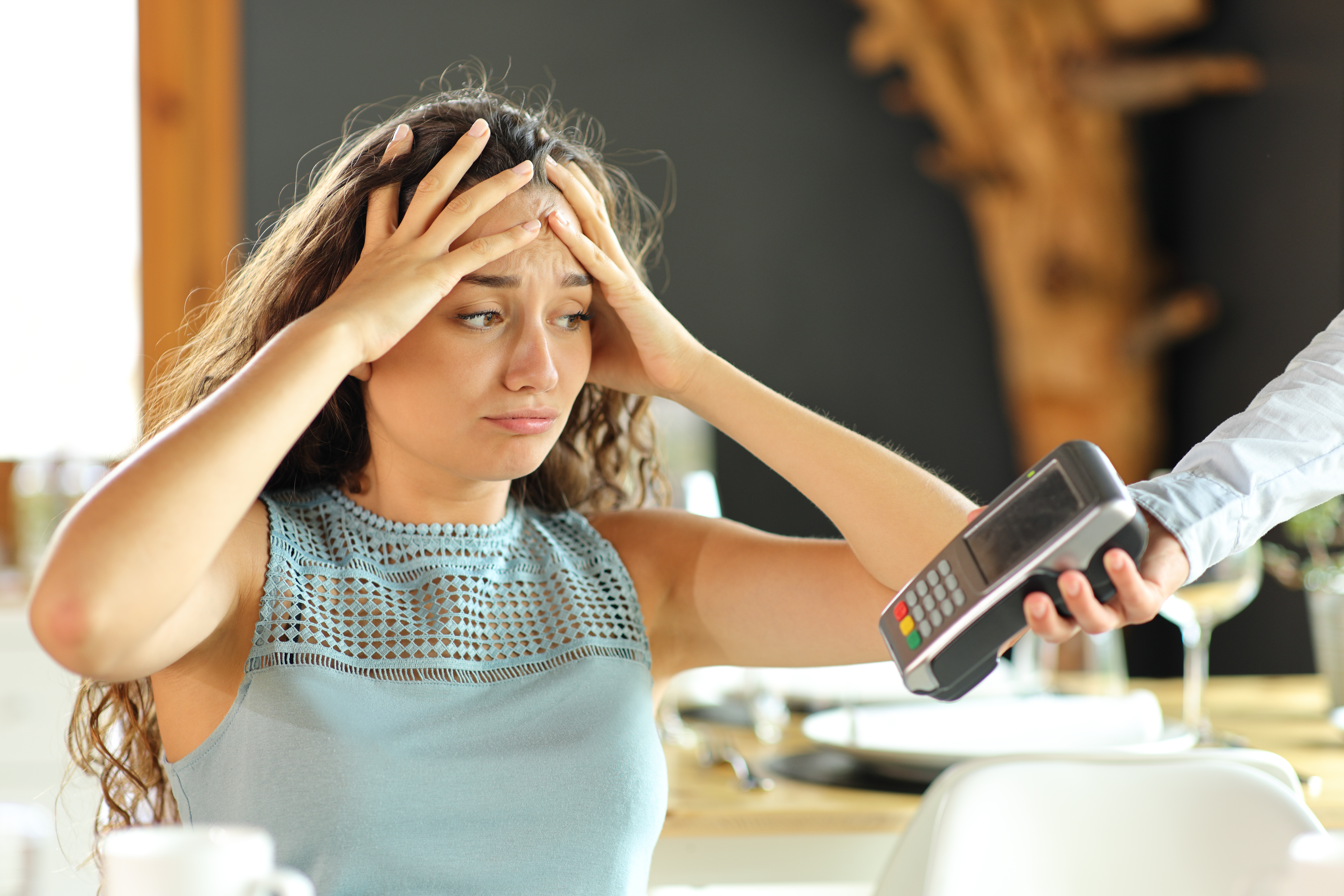 Una mujer parece desesperada mientras le entregan una máquina de tarjetas de crédito. | Foto: Shutterstock
