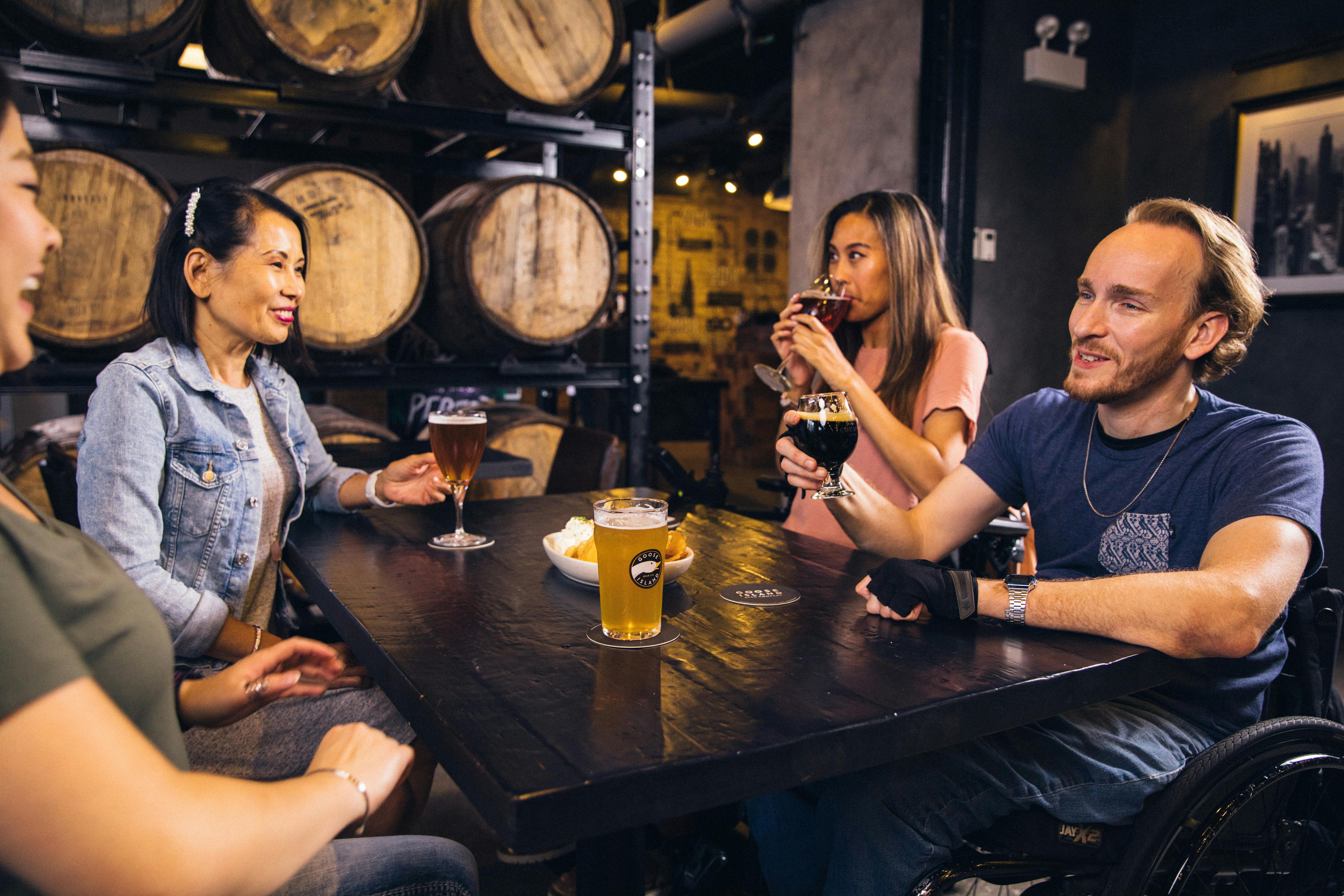 Gente sentada alrededor de una mesa y bebiendo cerveza | Fuente: Pexels