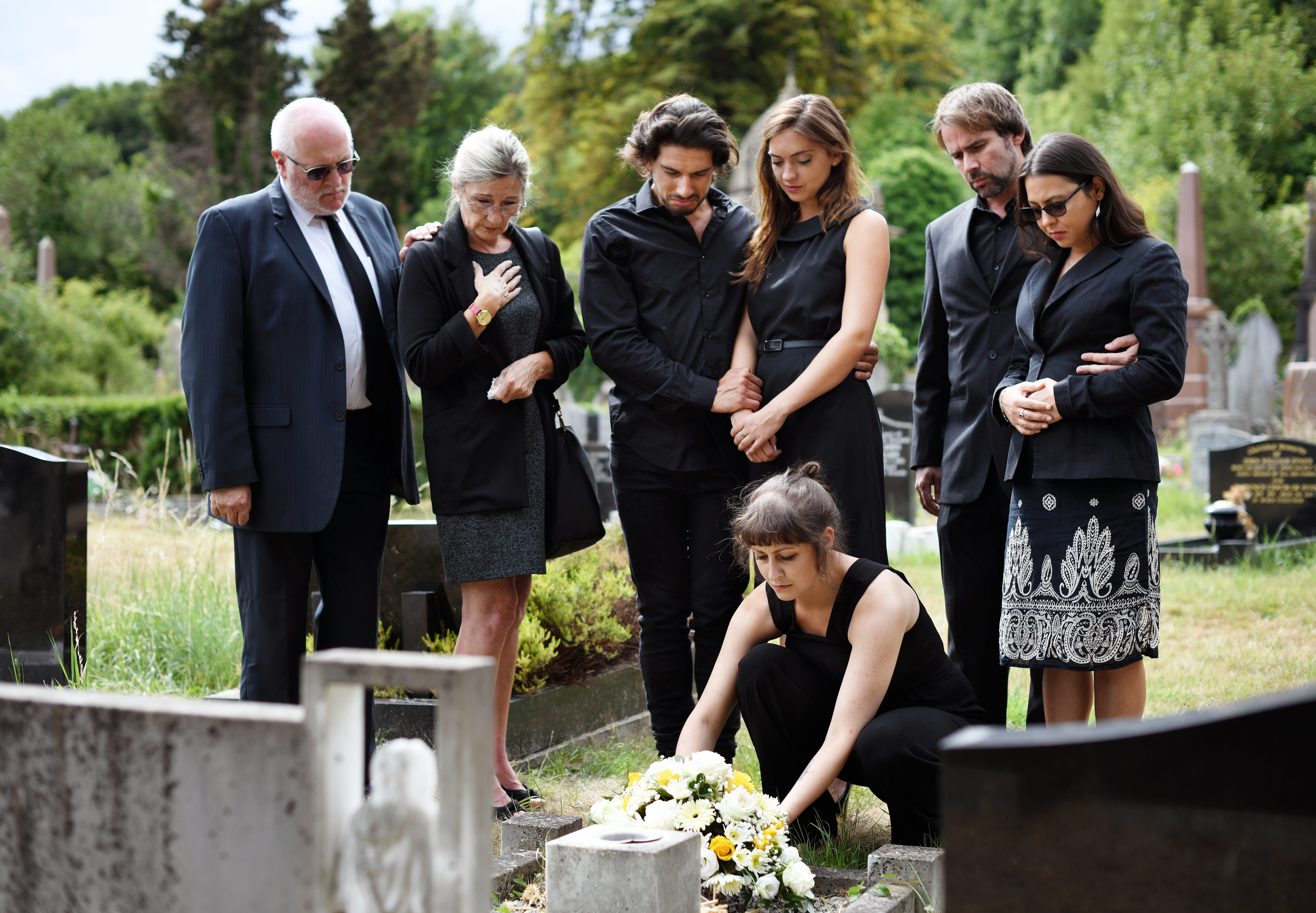 Familia alrededor de una tumba en un cementerio | Foto: Shutterstock