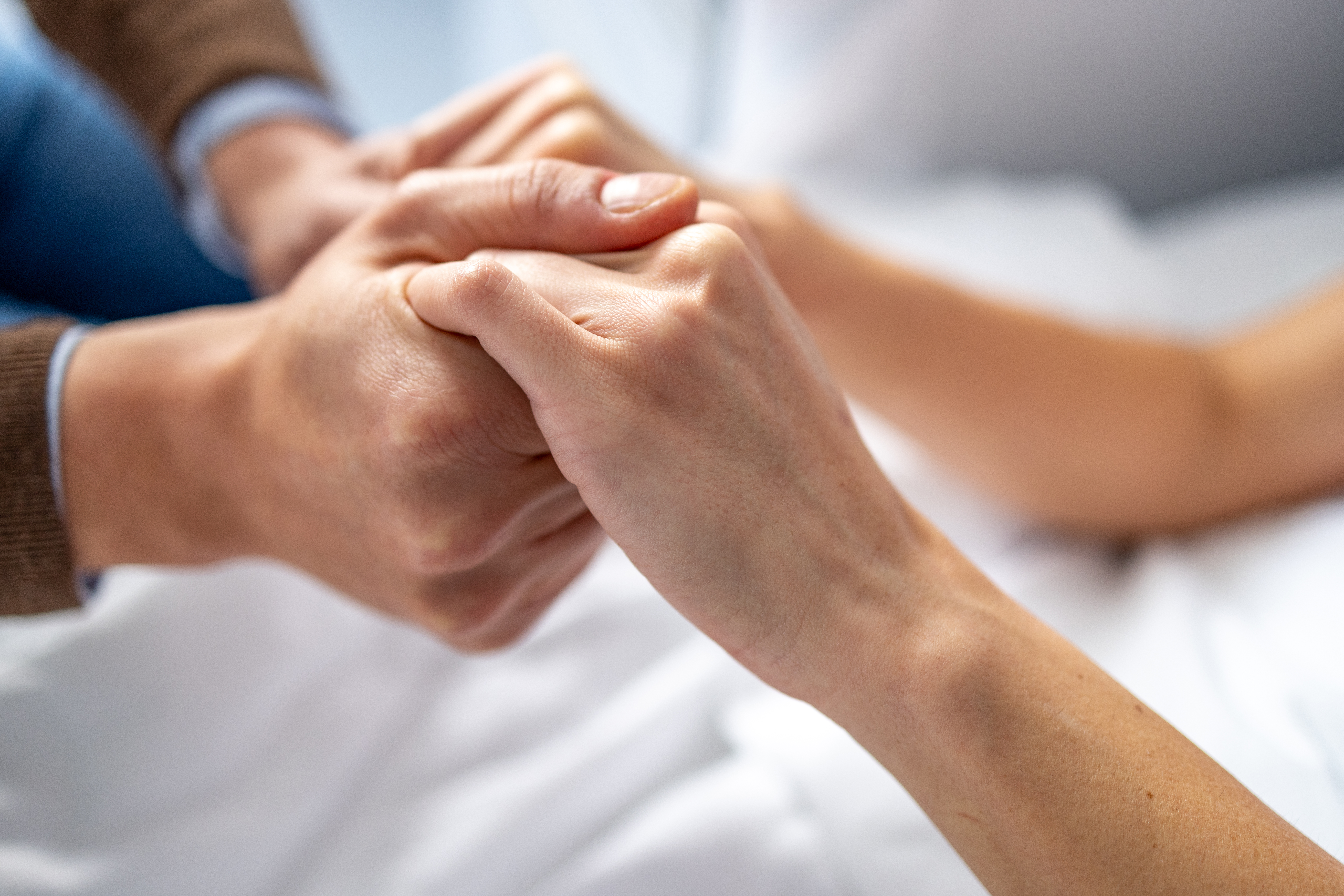 Hombre cogiendo de la mano a una mujer en la cama de un hospital. | Foto: Getty Images