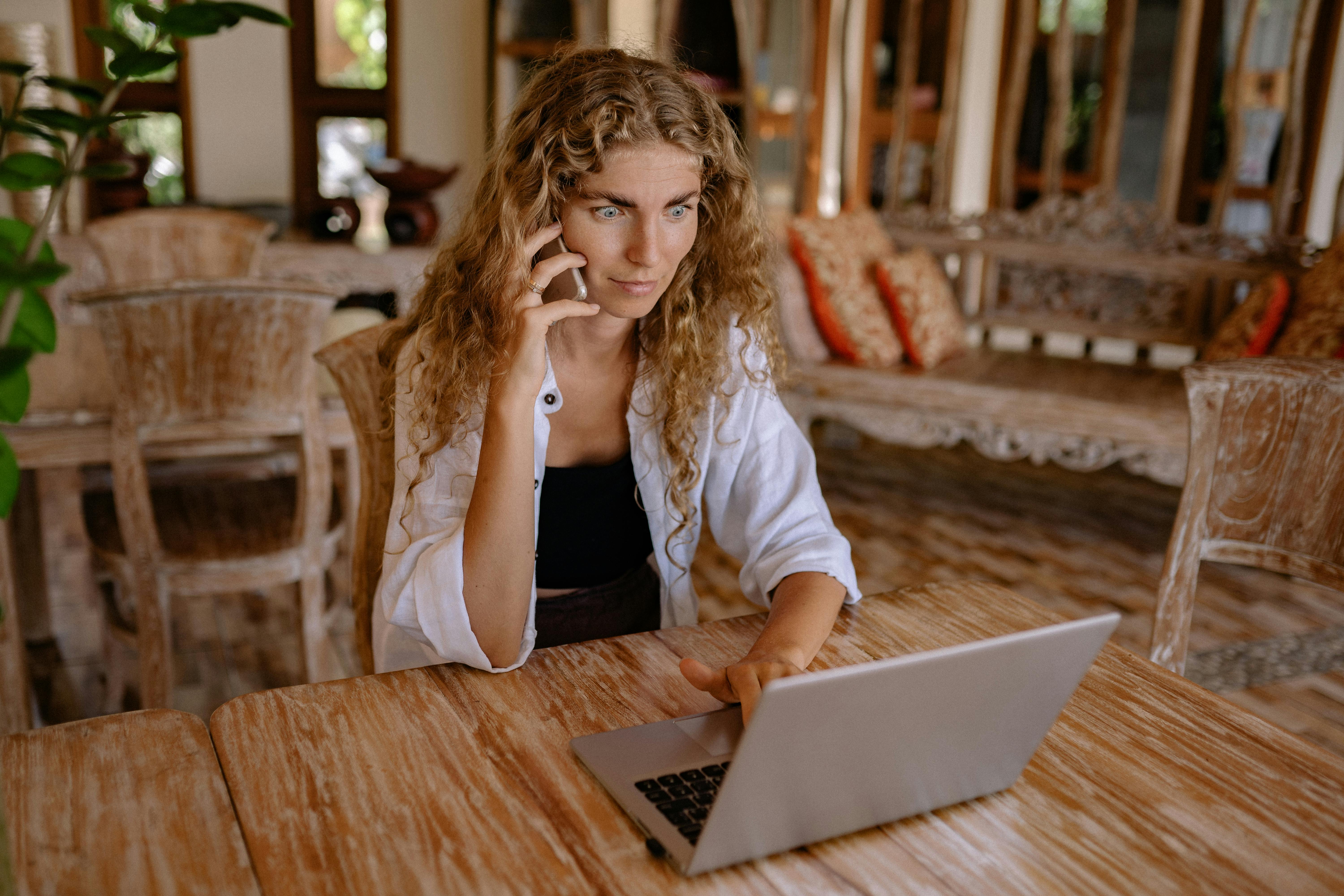 Una mujer hablando por teléfono mientras usa un portátil | Fuente: Pexels