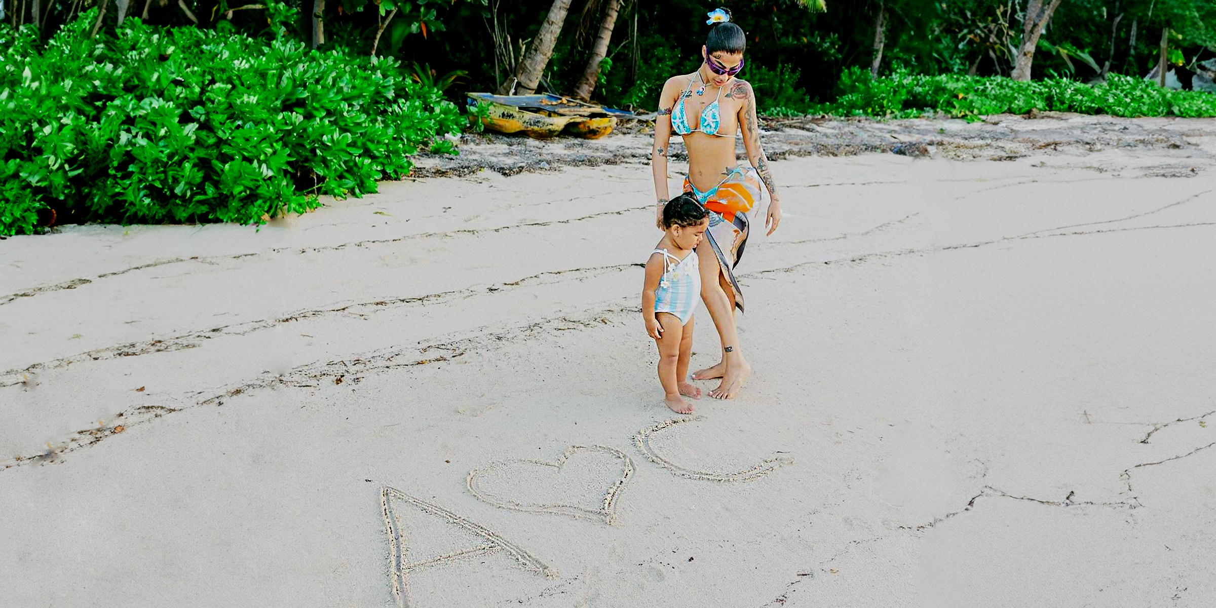 Yailín con su hija y letras "A" y "C" con un corazón en la arena. | Fuente: Instagram.com/yailinlamasviralreal