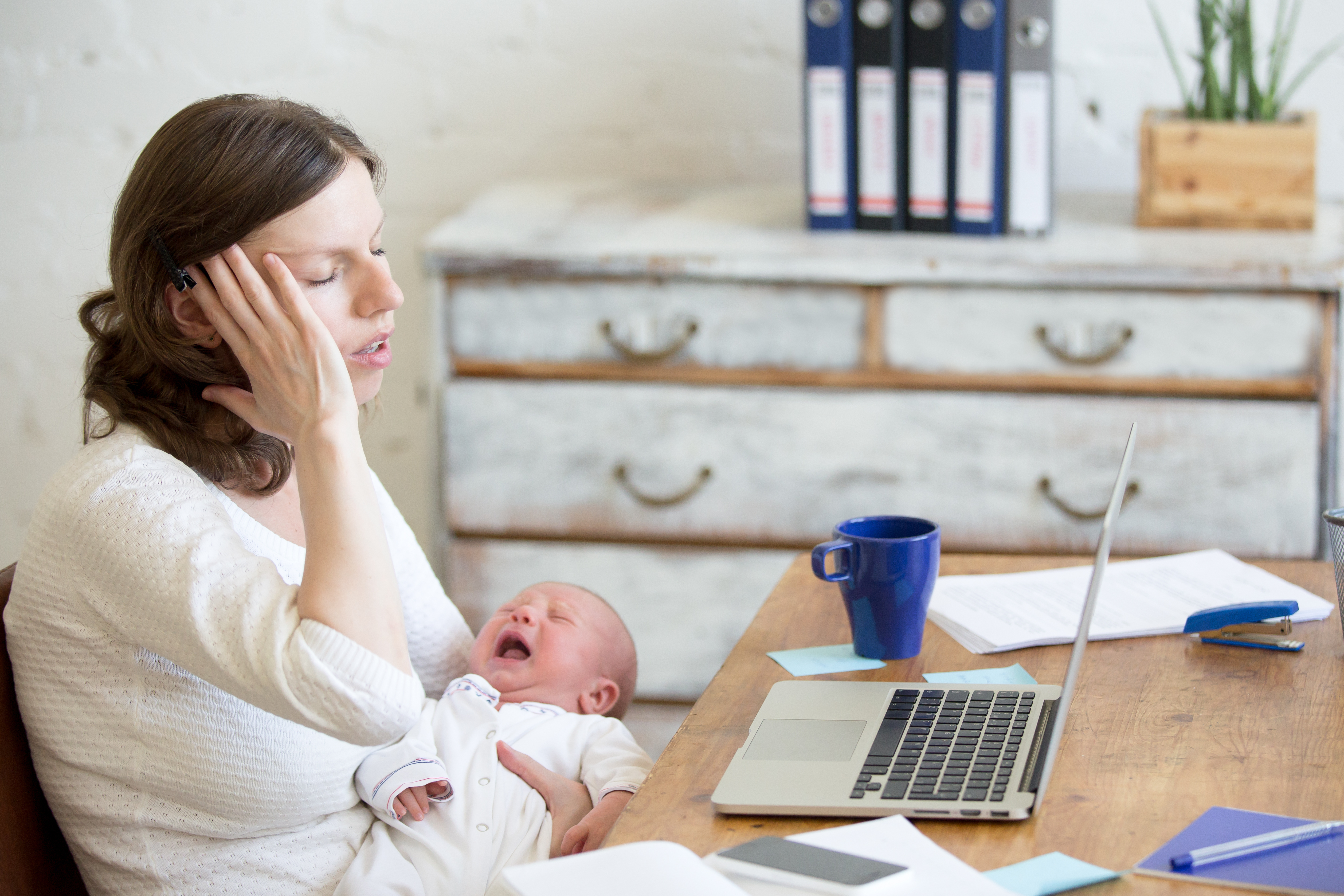 Una mujer parece estresada mientras sostiene a un bebé recién nacido que llora | Fuente: Shutterstock