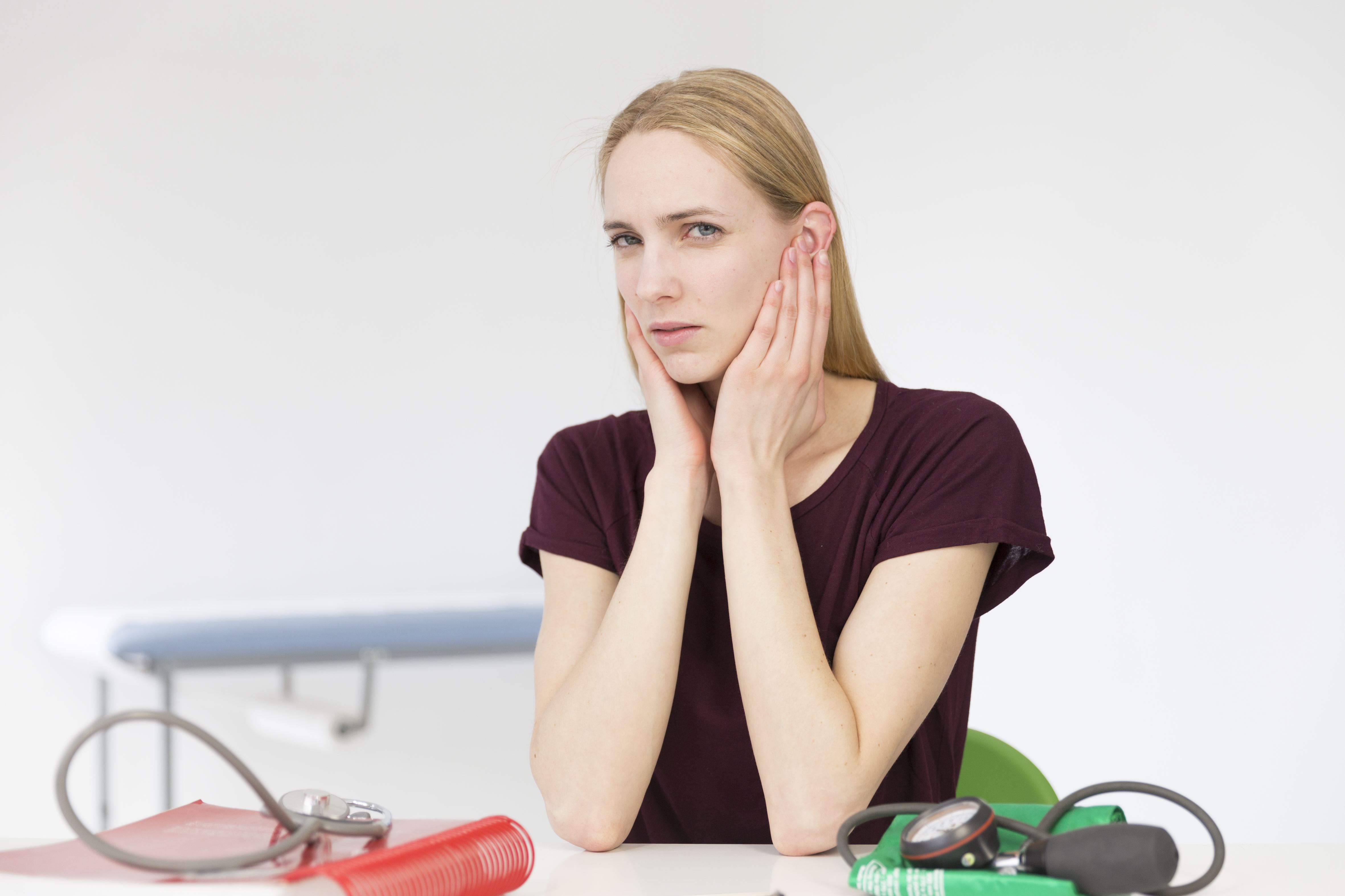 Mujer con visible malestar comentando los síntomas del dolor de oídos durante una consulta | Fuente: Getty Images