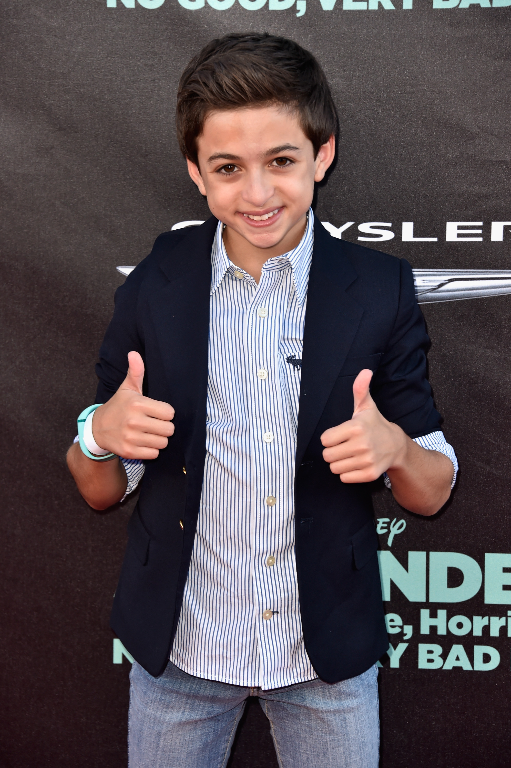 Sonríe a los fotógrafos en el estreno de la película de Disney "Alexander and the Terrible, Horrible, No Good, Very Bad Day" en el teatro El Capitán de Hollywood, California, vestida con una chaqueta azul marino, una camisa a rayas azules y blancas y unos vaqueros claros. | Fuente: Getty Images