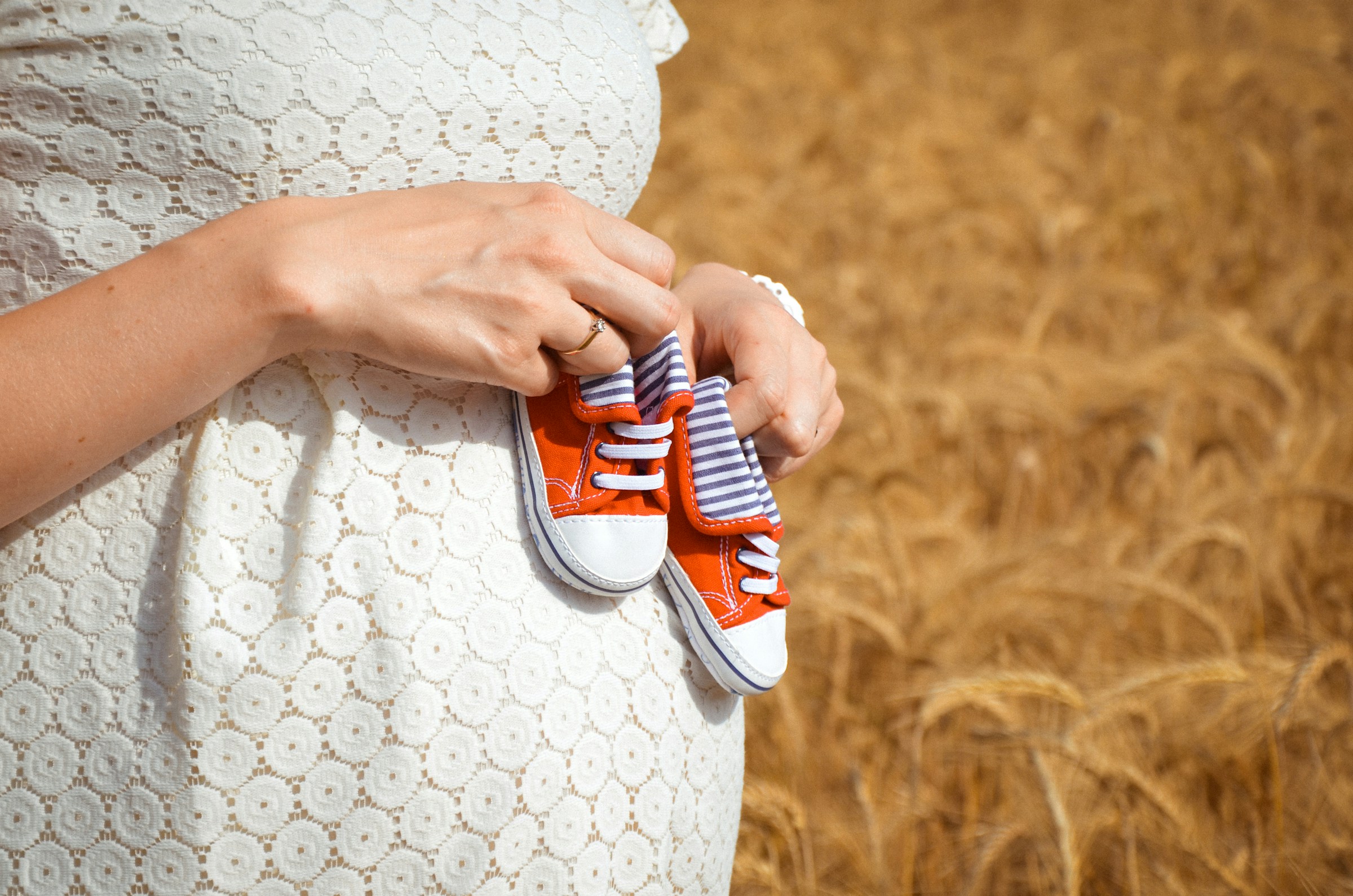 Una mujer embarazada sosteniendo unos zapatitos de bebé | Fuente: Unsplash