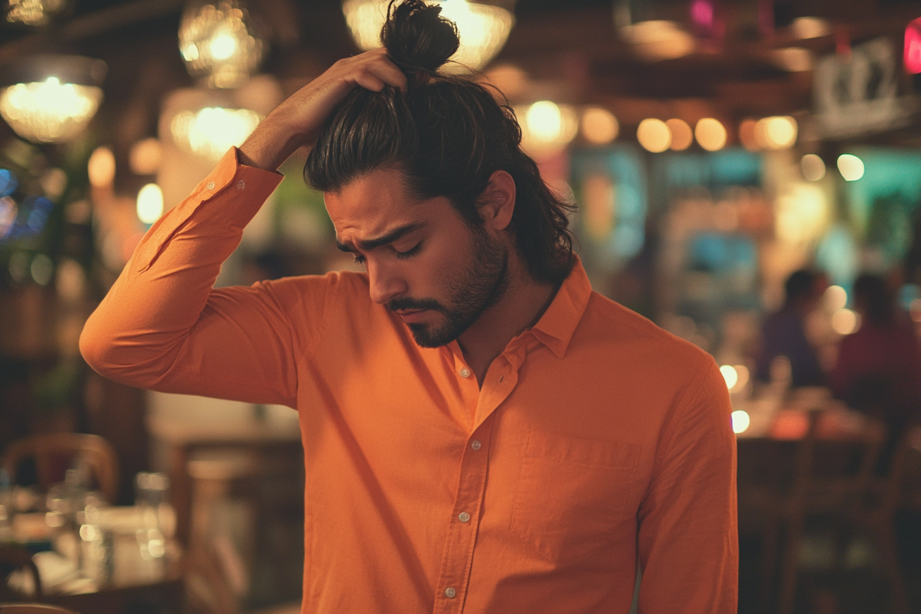 Un hombre de pie en un restaurante, tocándose el pelo, con aspecto triste y cansado | Fuente: Midjourney