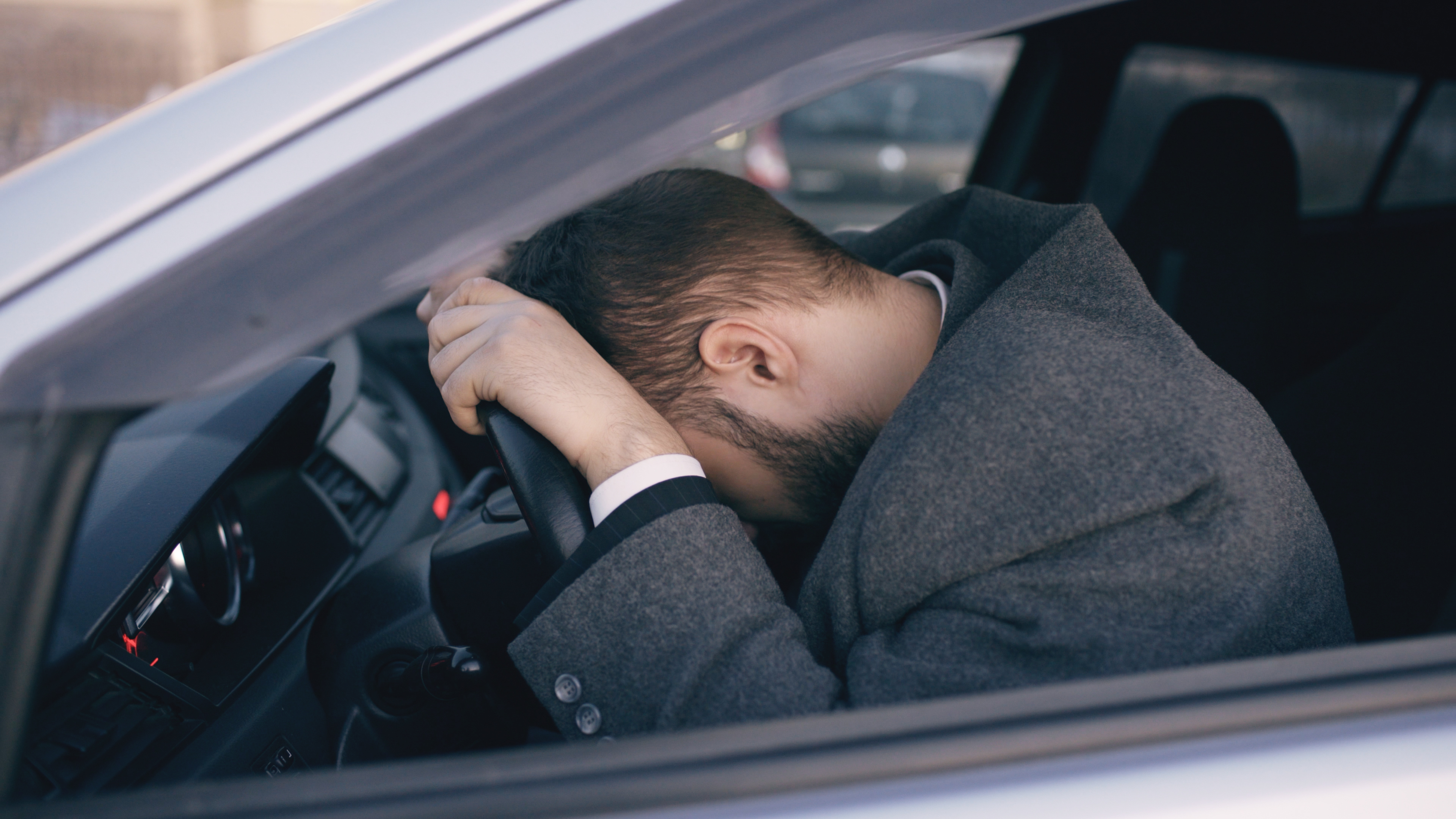 Hombre barbudo sentado en un Automóvil muy alterado y estresado después de una dura avería y moviéndose en un atasco. | Fuente: Shutterstock
