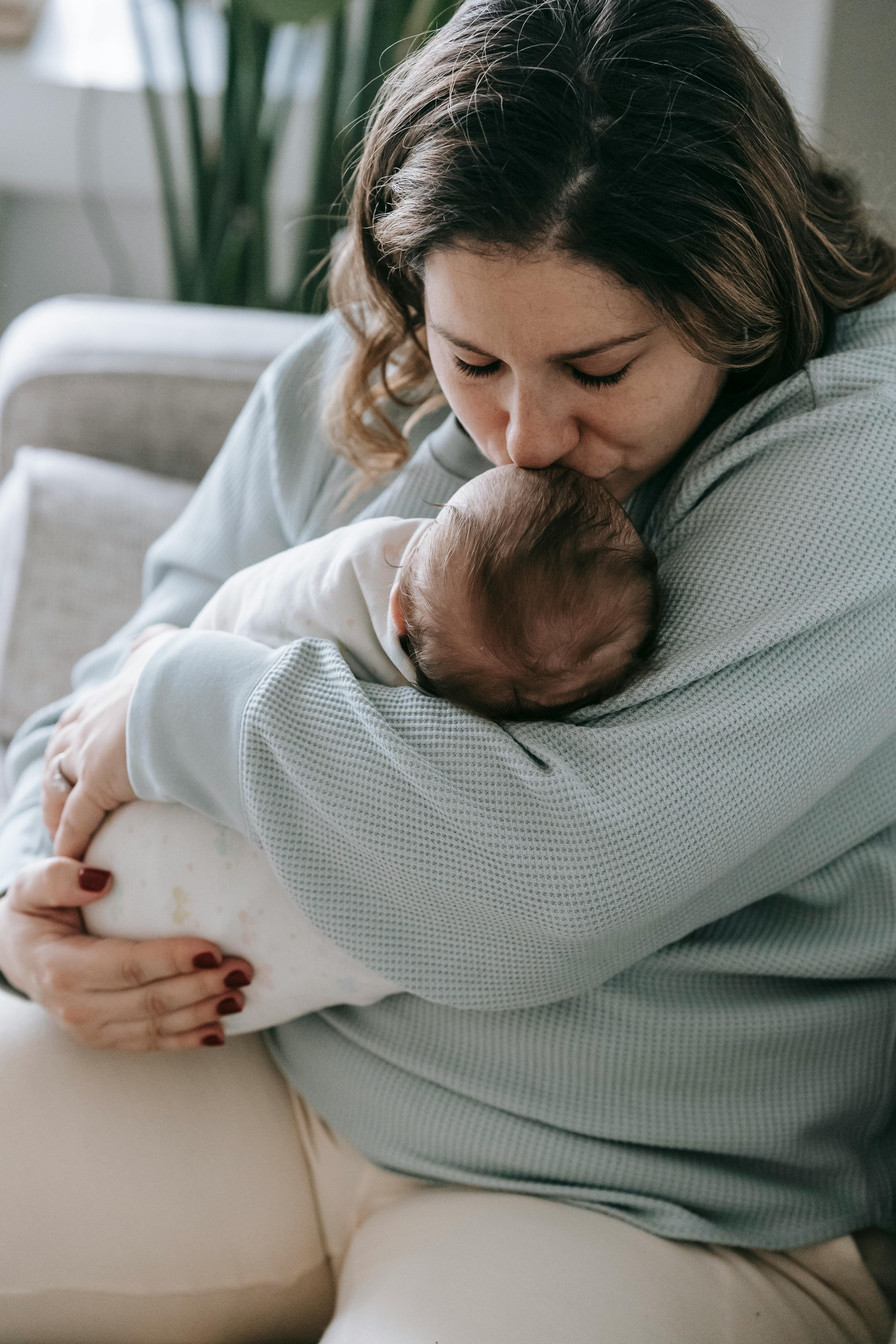 Una mujer besando la frente de su bebé | Fuente: Pexels