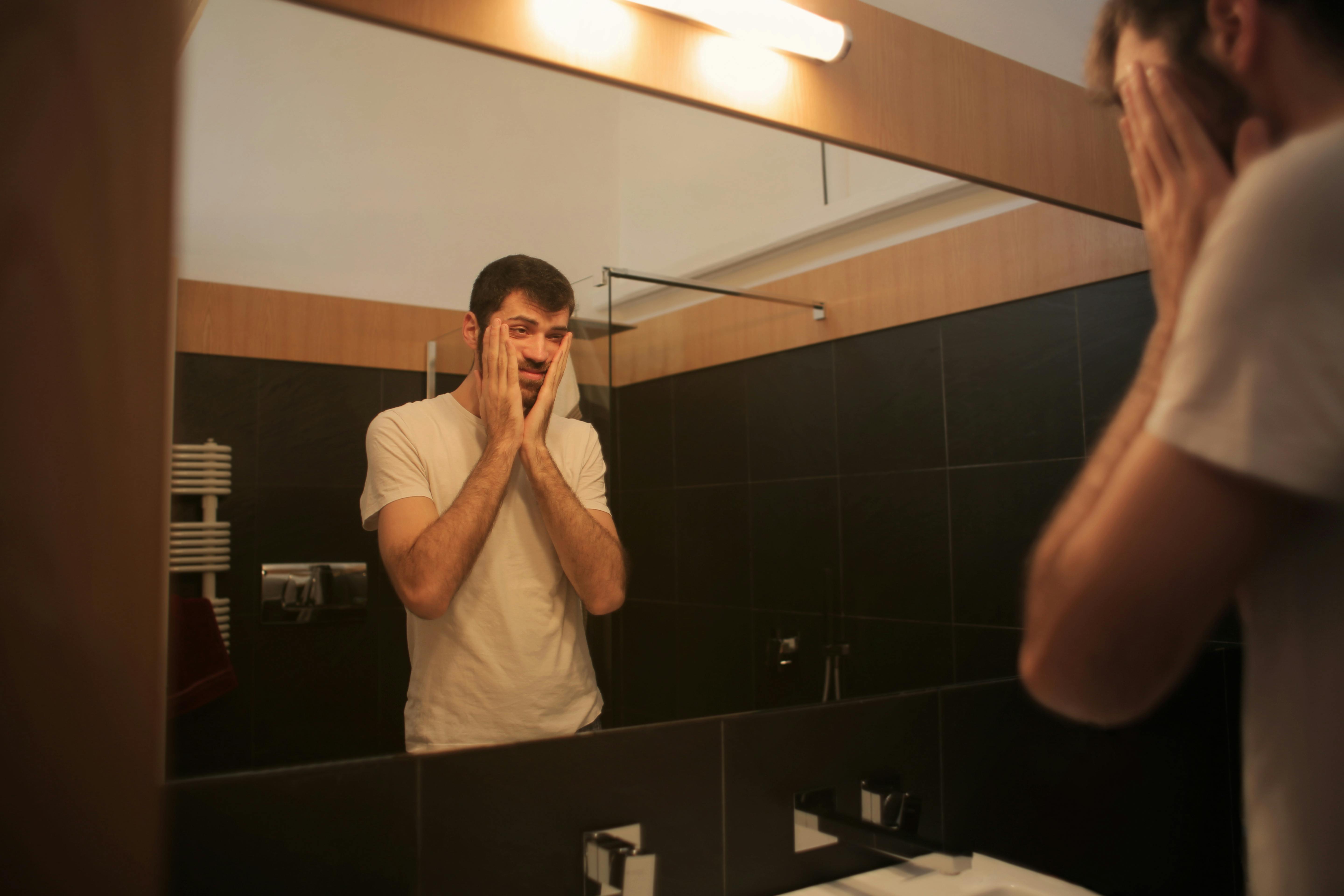 Un hombre frustrado mirándose en un espejo | Fuente: Pexels