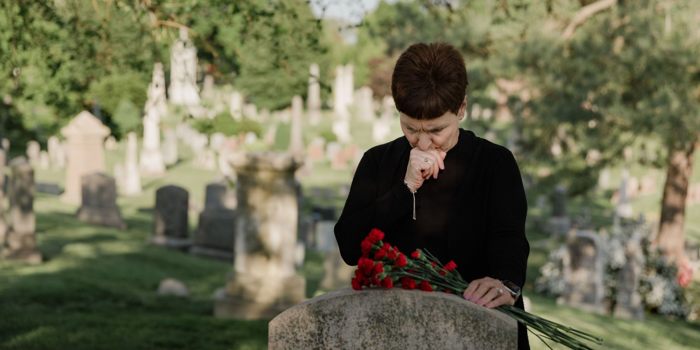Una mujer con un ramo de flores en una tumba | Fuente: Pexels