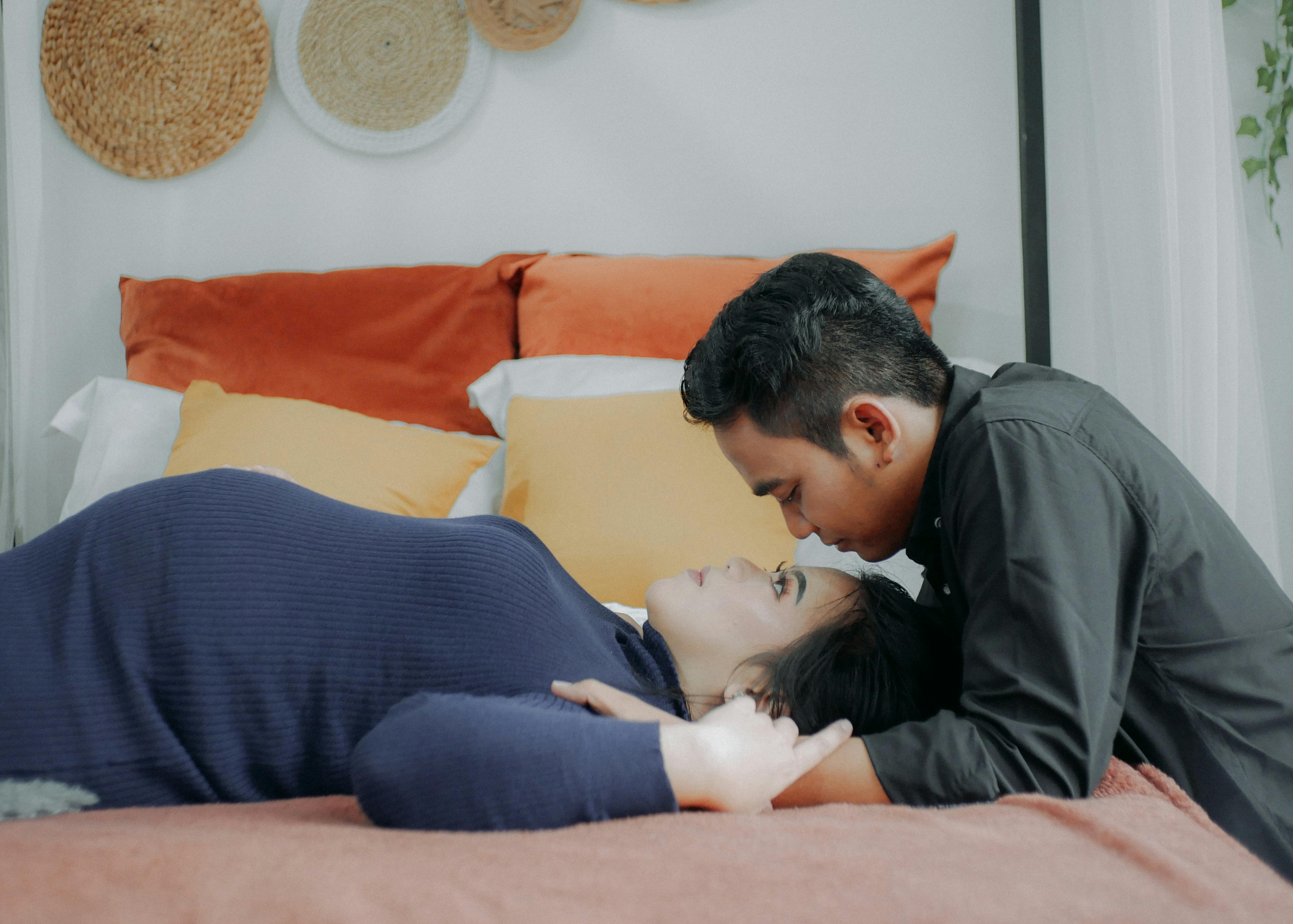 Una mujer embarazada y su marido mirándose en el dormitorio | Fuente: Pexels