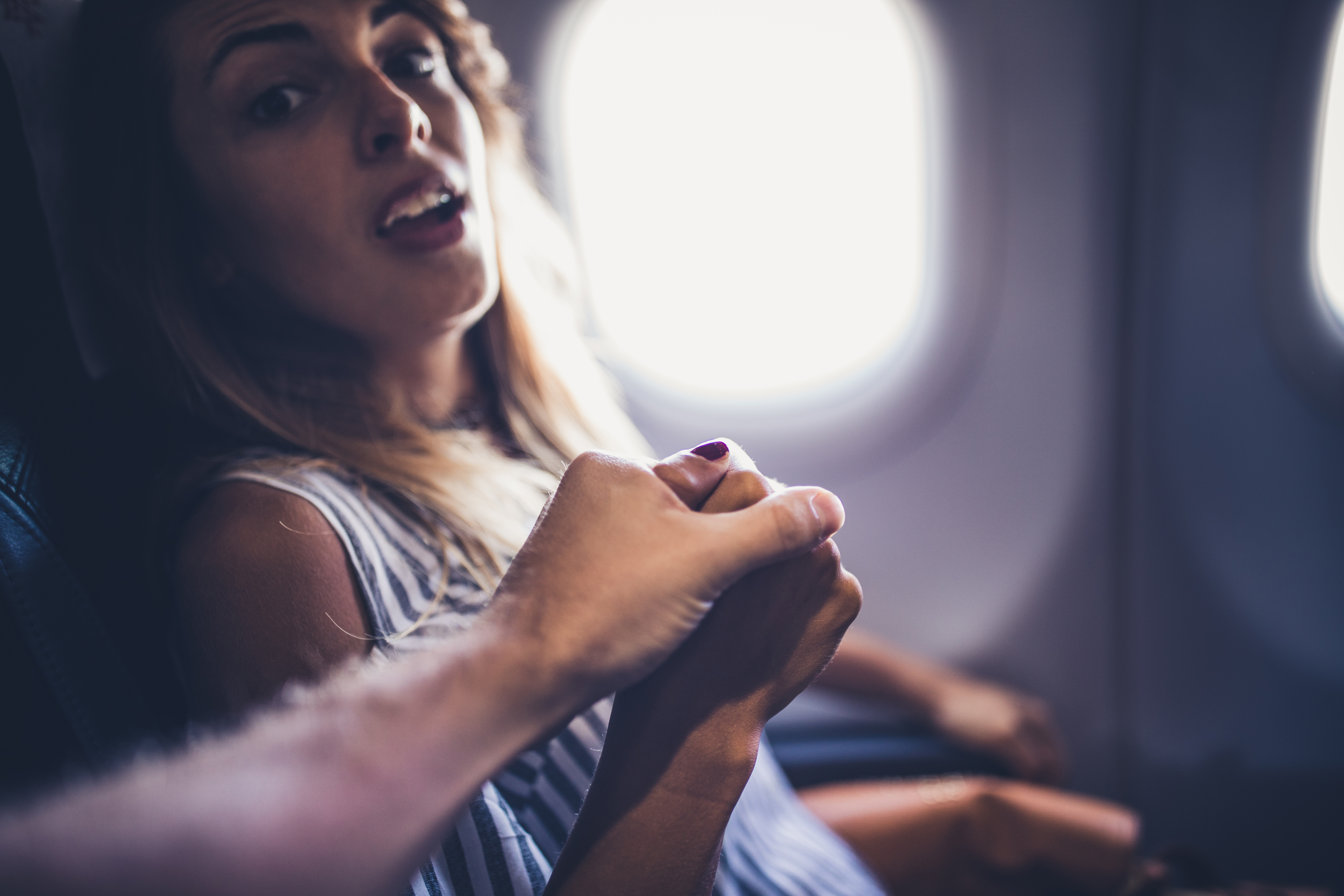Esposo coge de la mano a su asustada esposa en un avión | Fuente: Getty Images