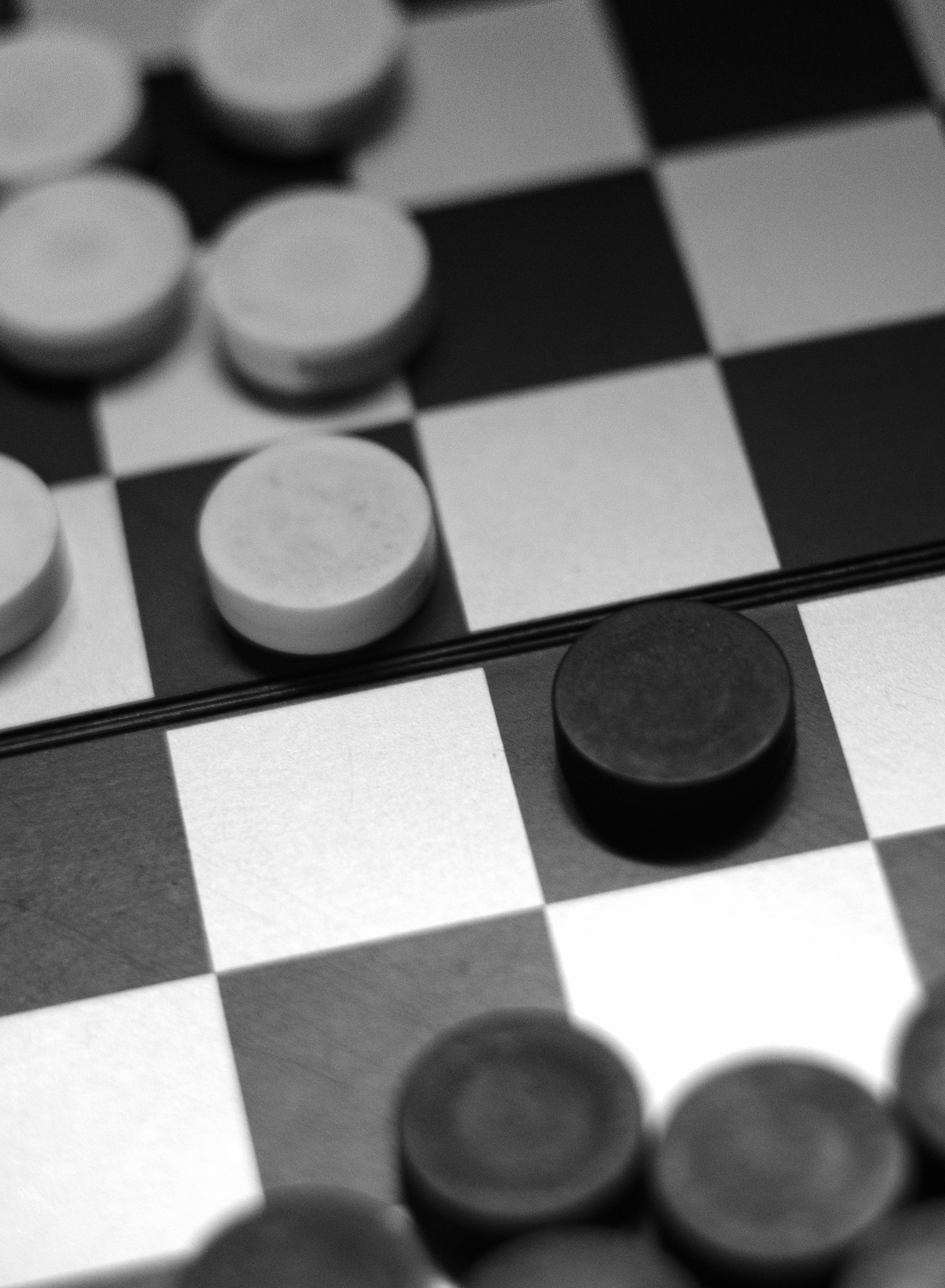 Piezas de damas blancas y negras sobre un tablero | Fuente: Pexels