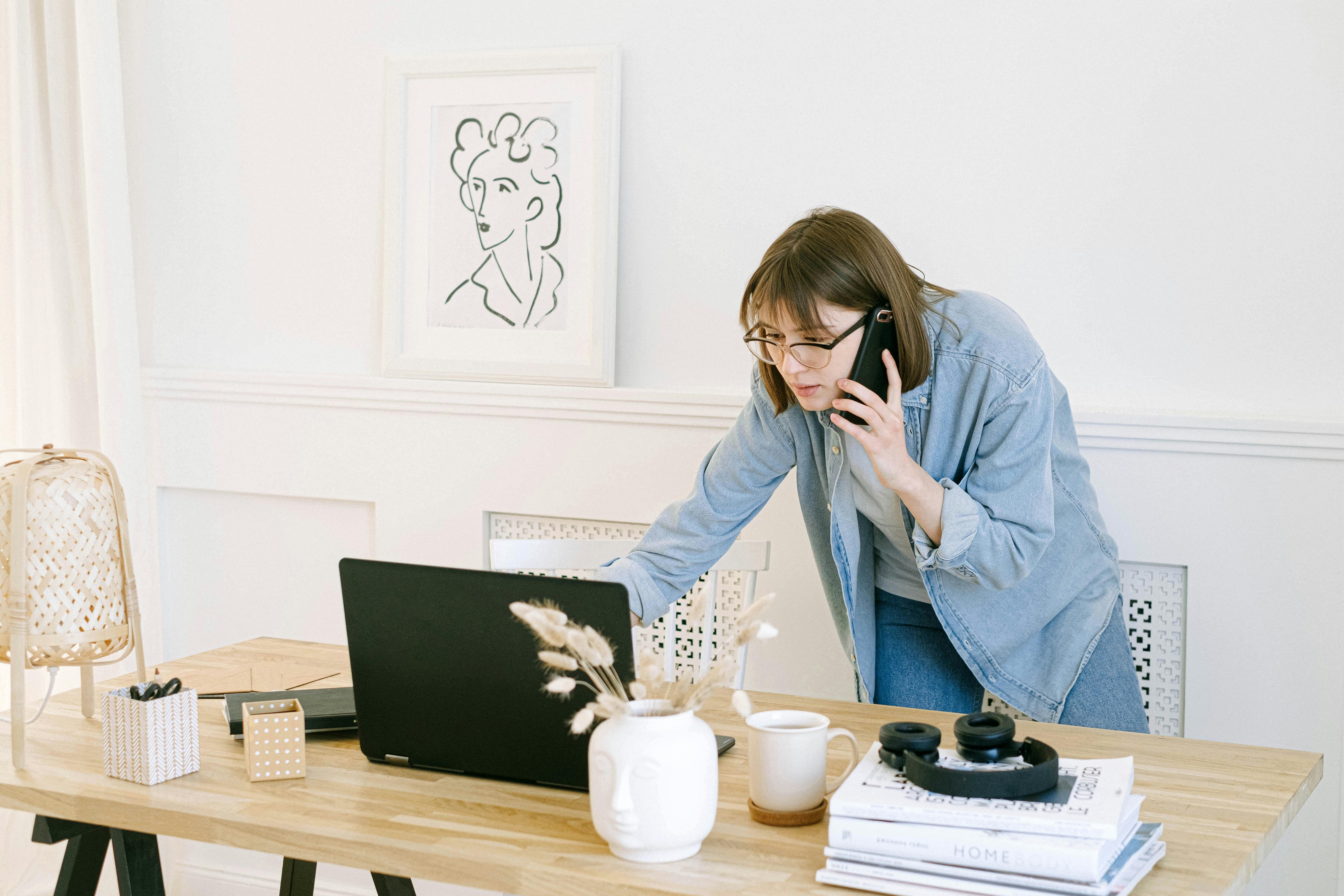 Mujer hablando por teléfono mientras mira un portátil | Fuente: Pexels