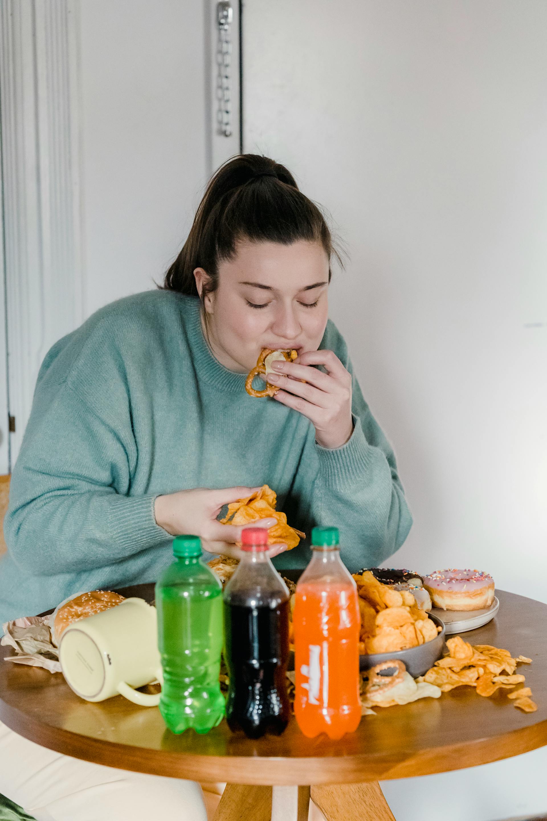 Una mujer comiendo comida basura | Fuente: Pexels