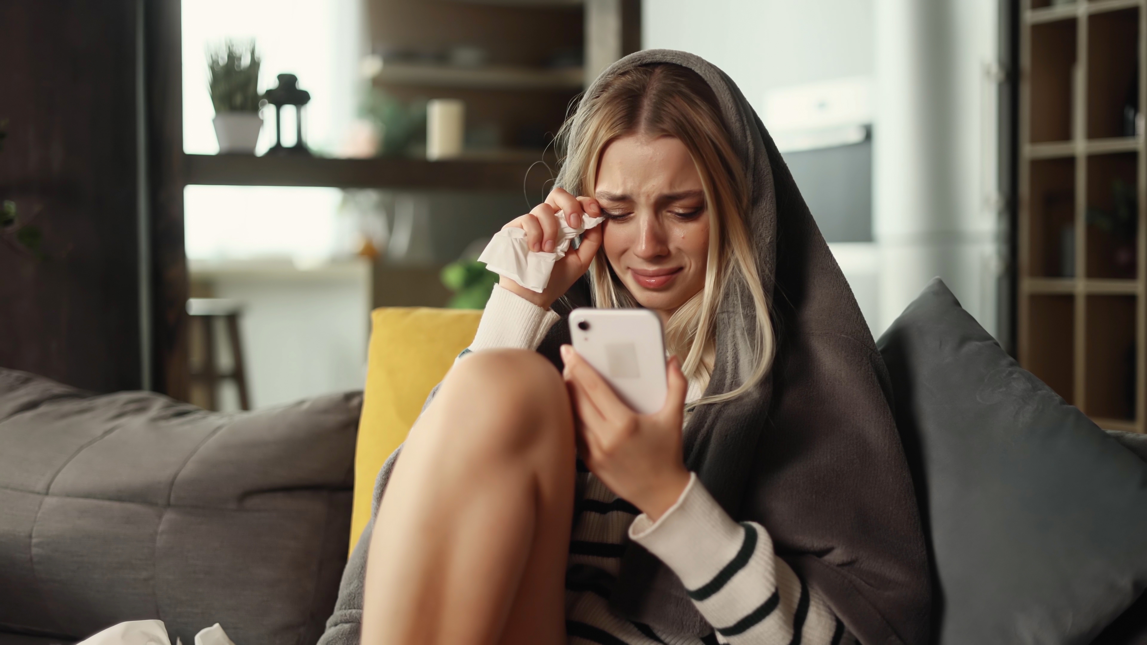 Una mujer llora mientras mira su teléfono | Fuente: Shutterstock
