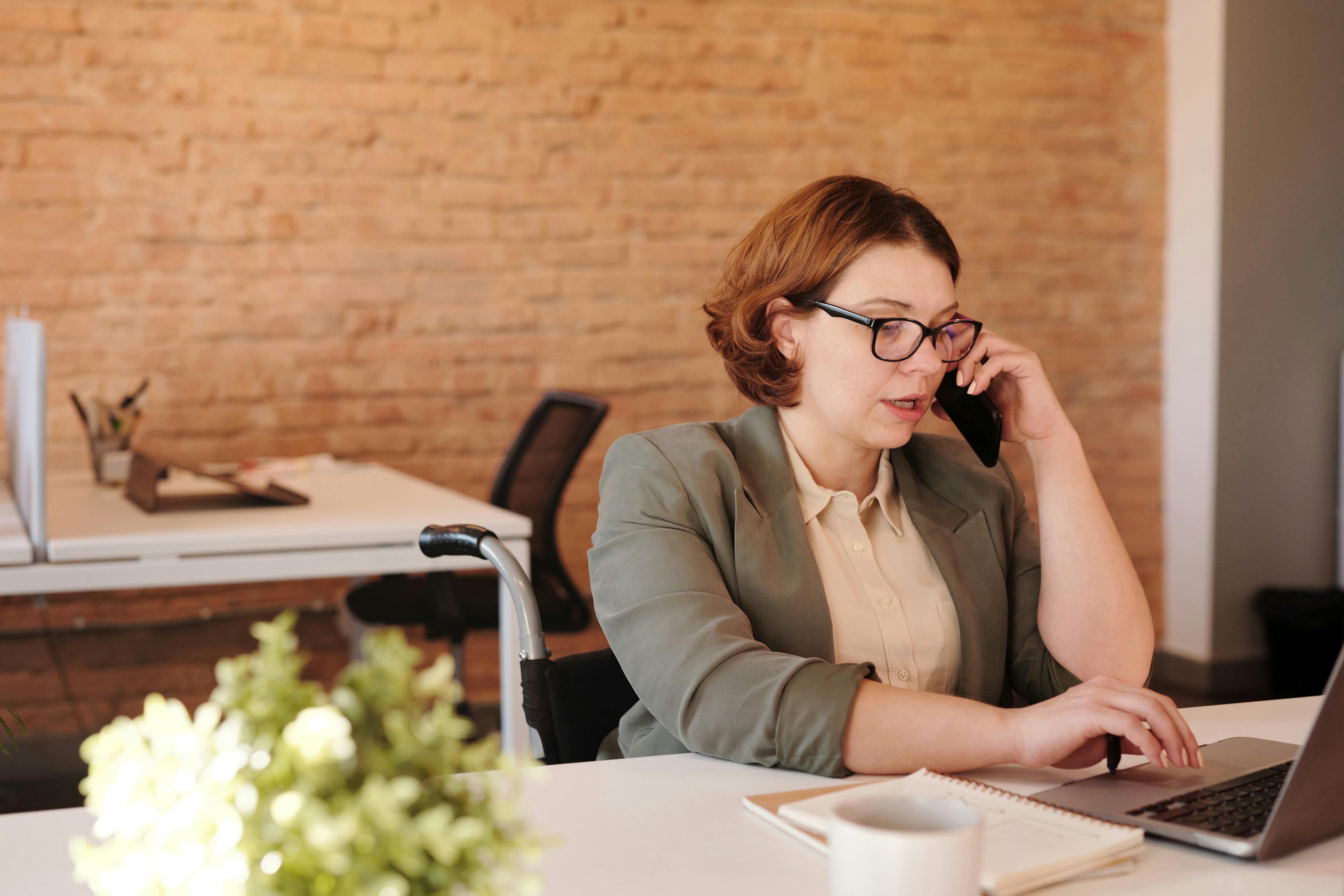 Una mujer hablando por teléfono mientras trabaja con un portátil | Fuente: Pexels