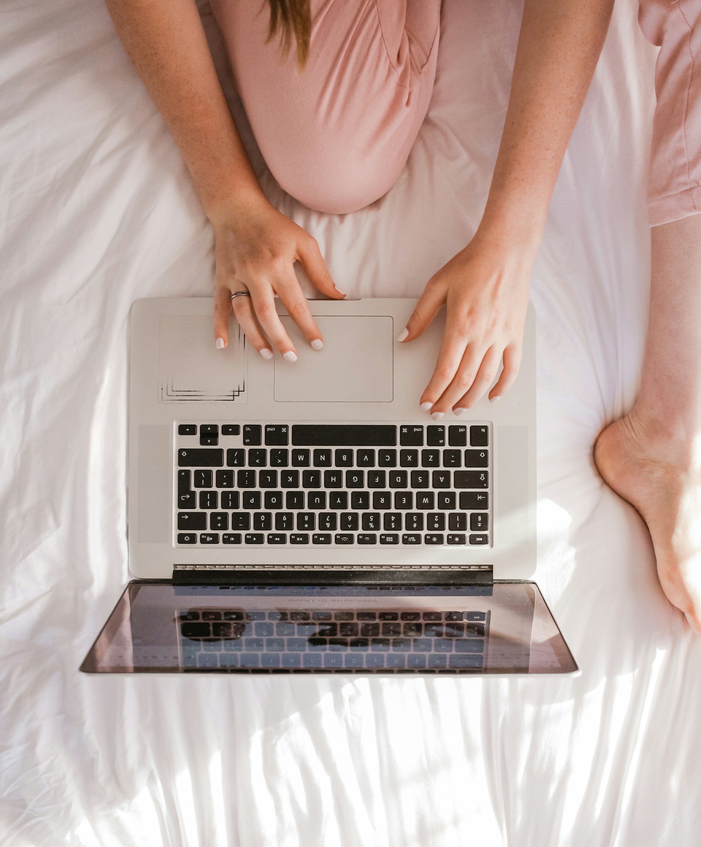 Primer plano de una mujer utilizando su portátil en la cama | Fuente: Unsplash