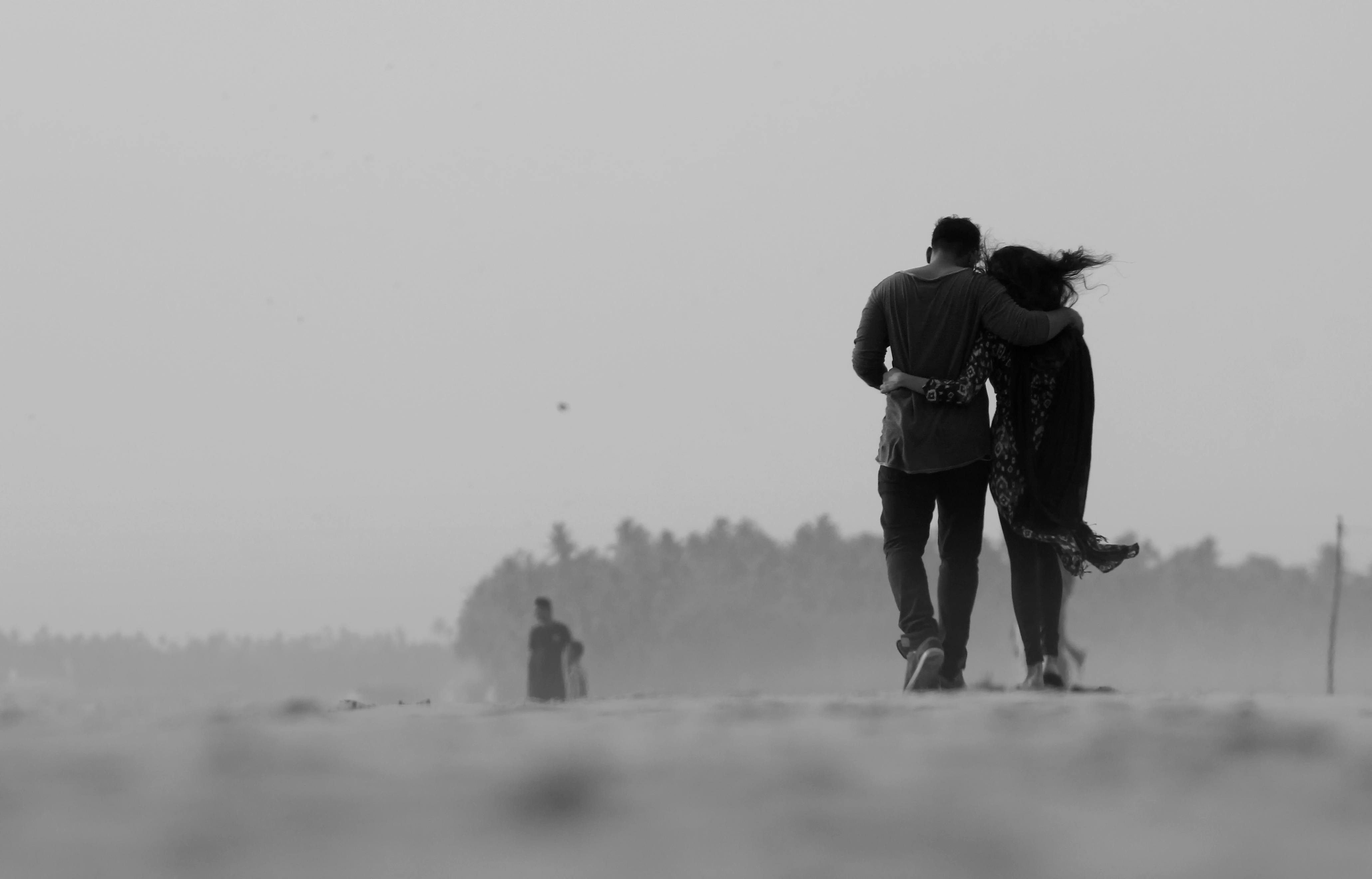Una foto en blanco y negro de una pareja apoyándose el uno en el otro y alejándose de la cámara | Foto: Pexels