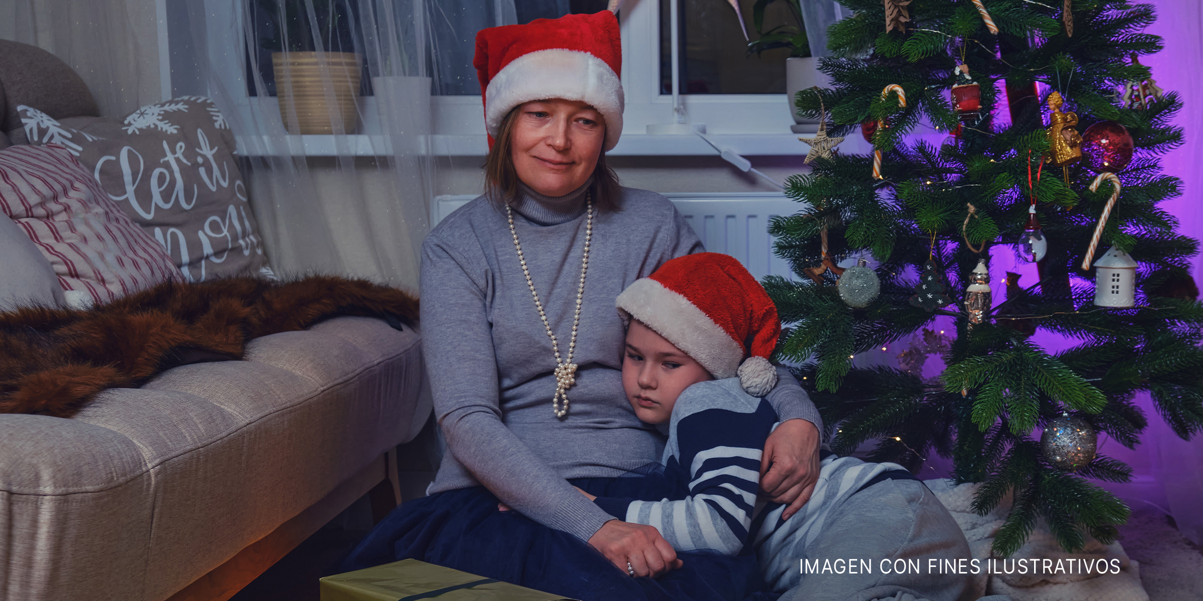 Madre e hijo sentados cerca del árbol de Navidad | Foto: Getty Images