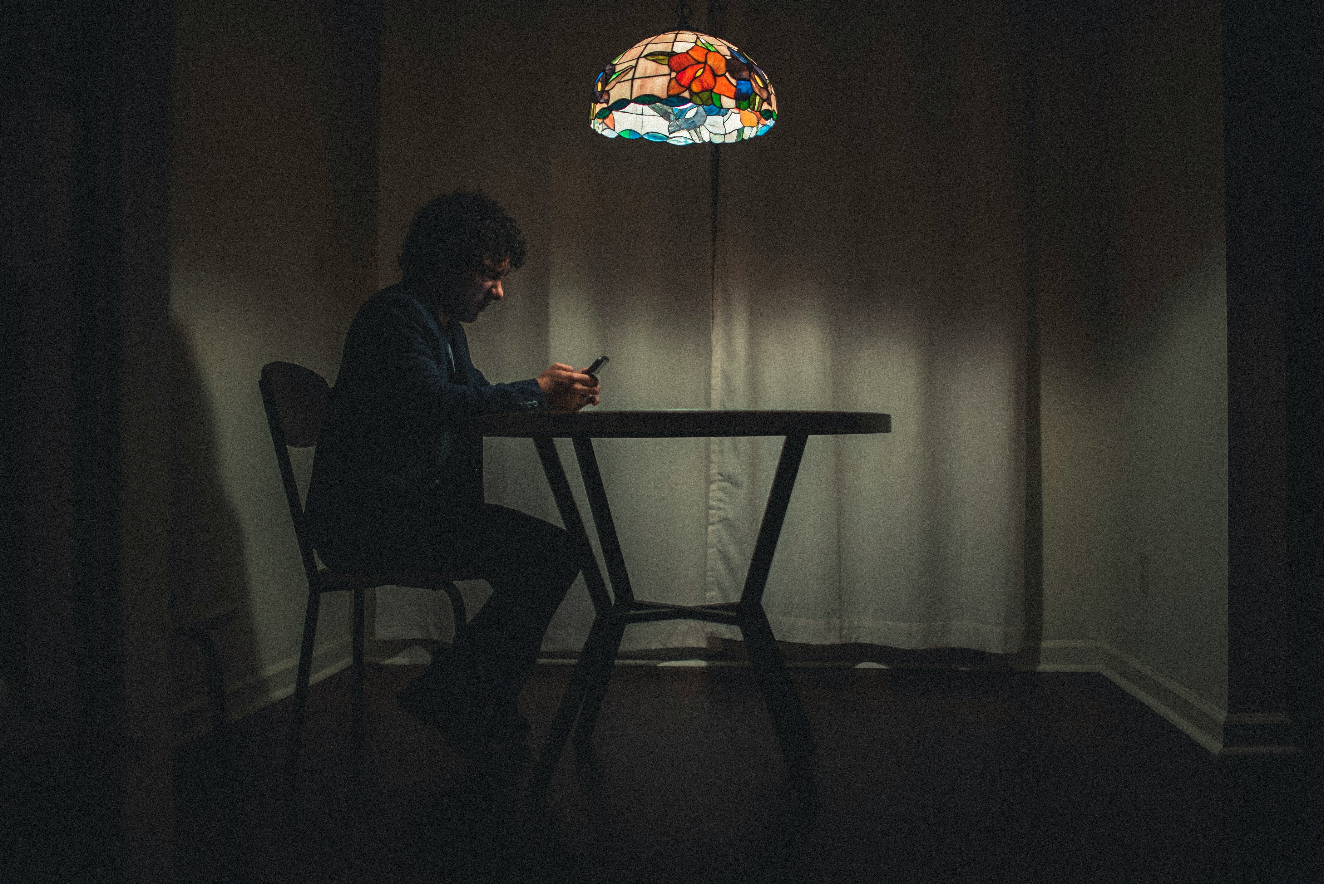 Un hombre sentado en una mesa y utilizando un celular | Fuente: Unsplash