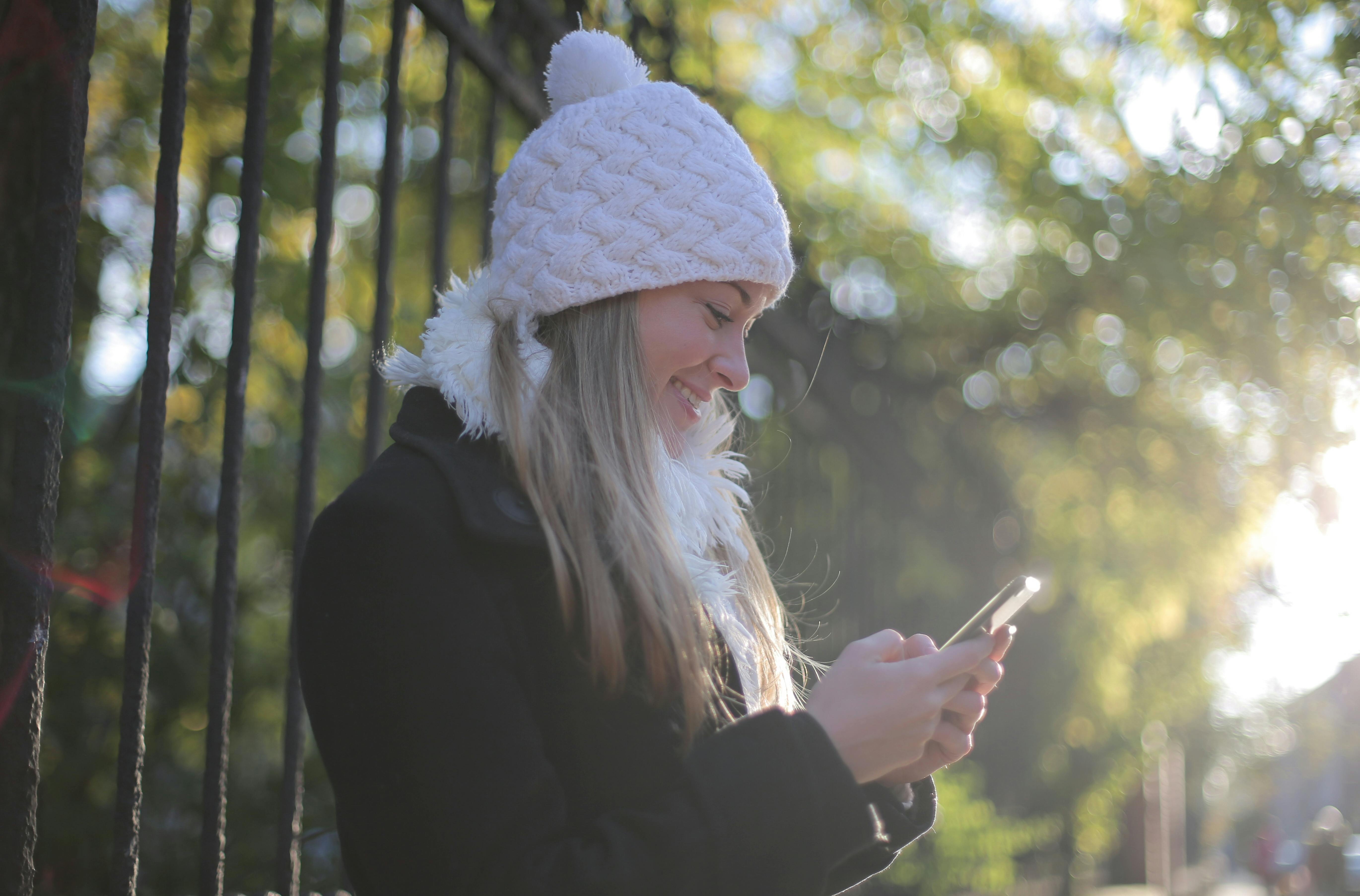 Una mujer sonriendo mientras mira su teléfono | Fuente: Pexels