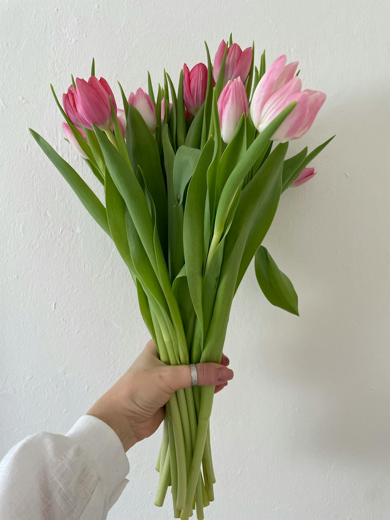 Immagine ritagliata di una donna che tiene in mano un mazzo di tulipani rosa | Fonte: Pexels