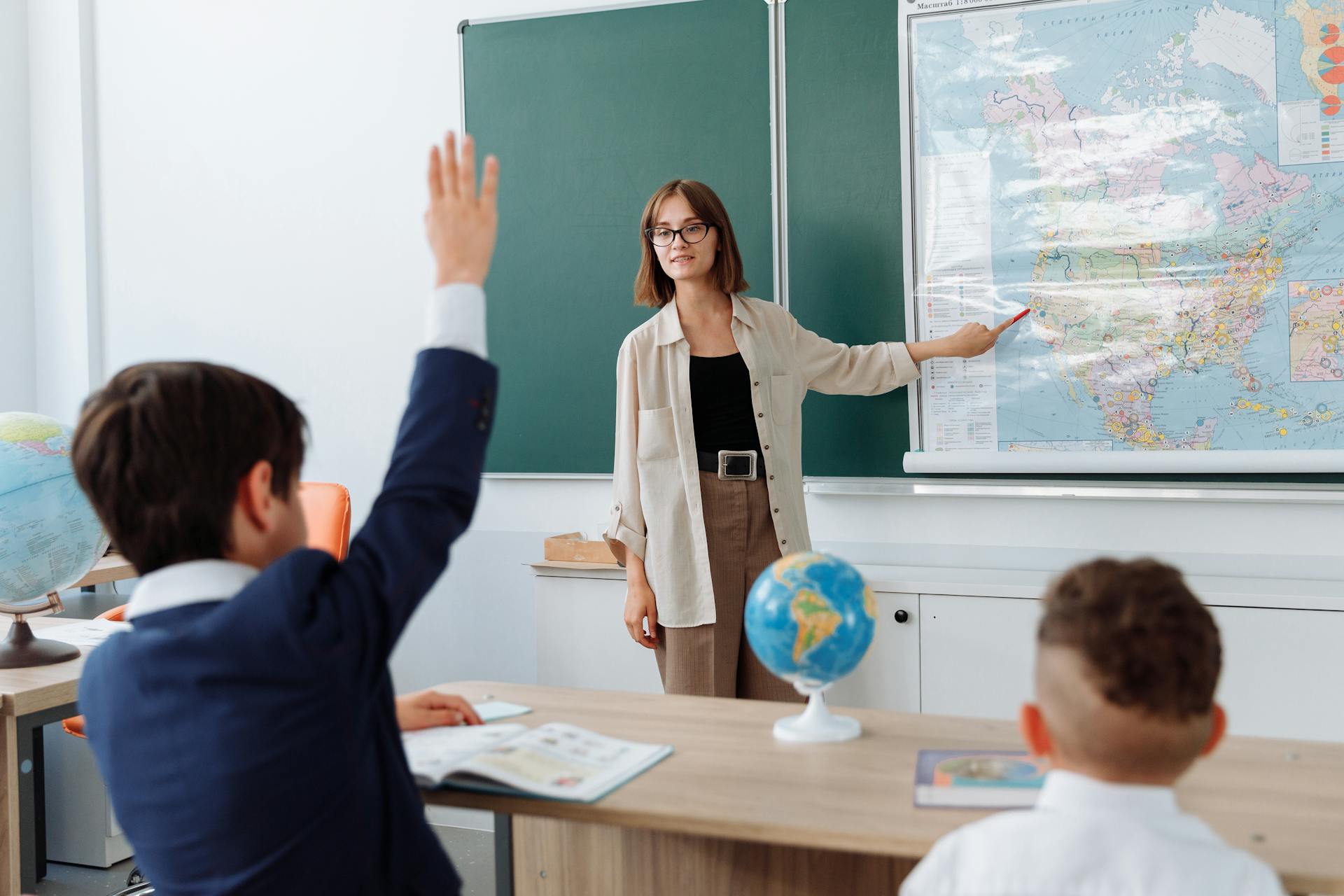 Un niño levantando la mano en clase de Geografía | Fuente: Pexels