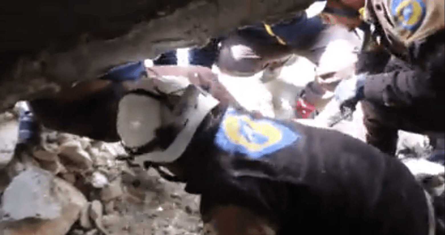 White Helmets filmados apresurándose para remover escombros para rescatar a dos cachorros. Fuente: YouTube / Daily Mail