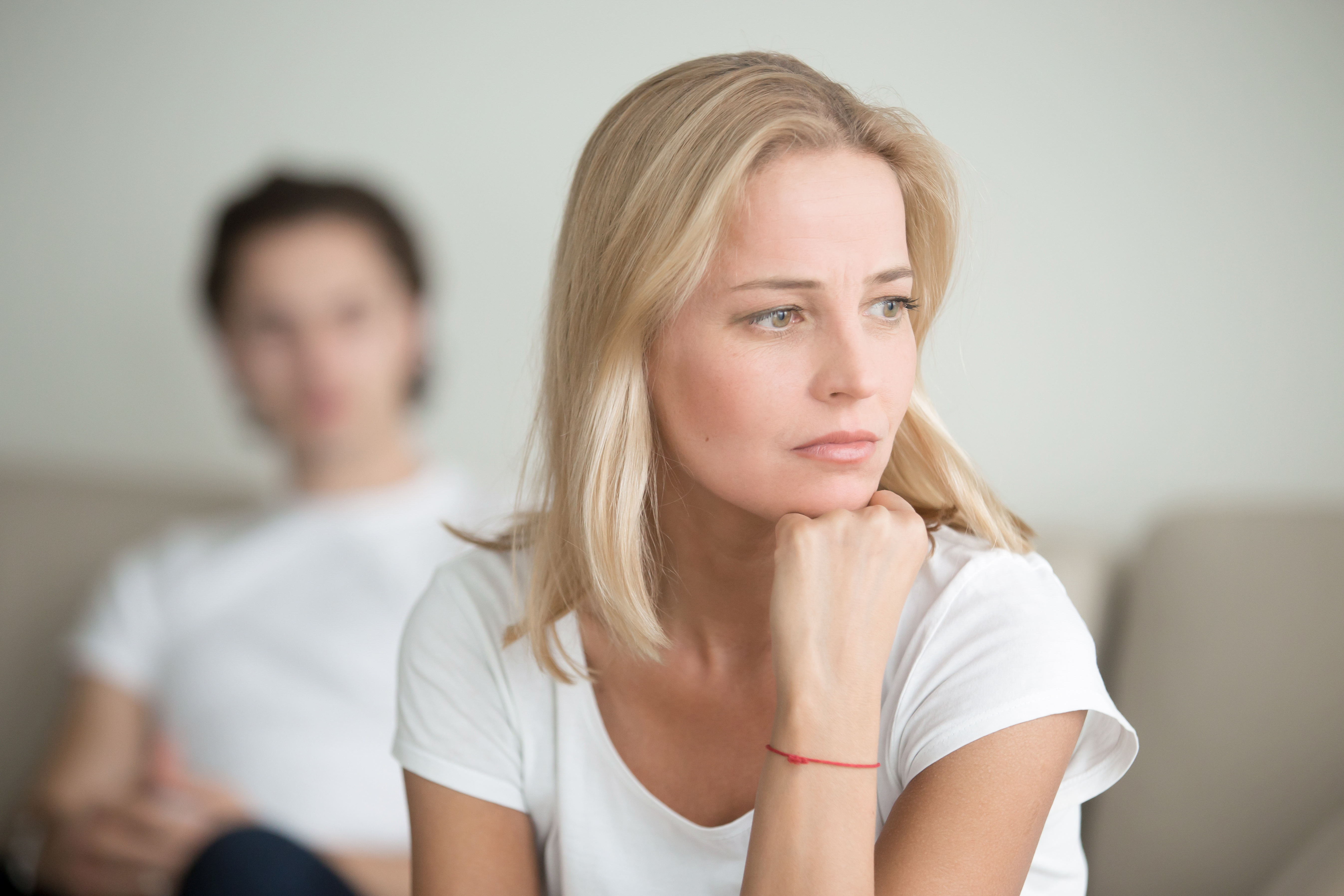Una mujer sumida en la contemplación mientras otro hombre la observa desde atrás | Fuente: Shutterstock