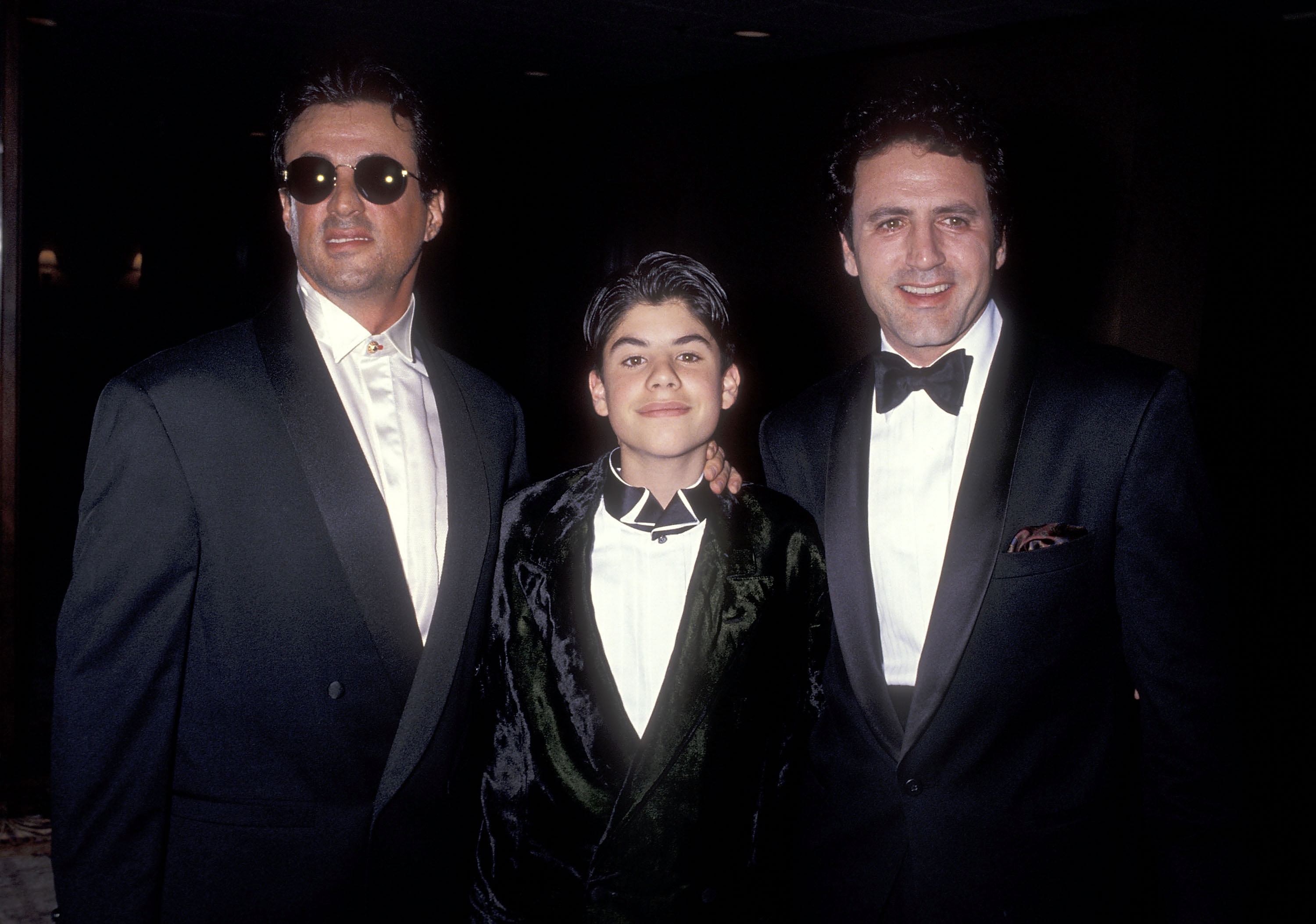 El niño, su padre y su hermano en el Quinto Desfile Anual de Moda y Cena Benéfica Saludo a Gianni Versace patrocinado por la Industria de la Moda de California Amigos del Proyecto SIDA Los Ángeles en Century City, California, el 13 de febrero de 1991. | Foto: Getty Images