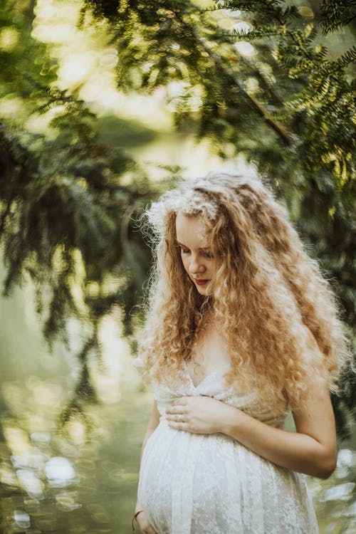 Mujer joven embarazada mira con ternura su abdomen. | Foto: Pexels