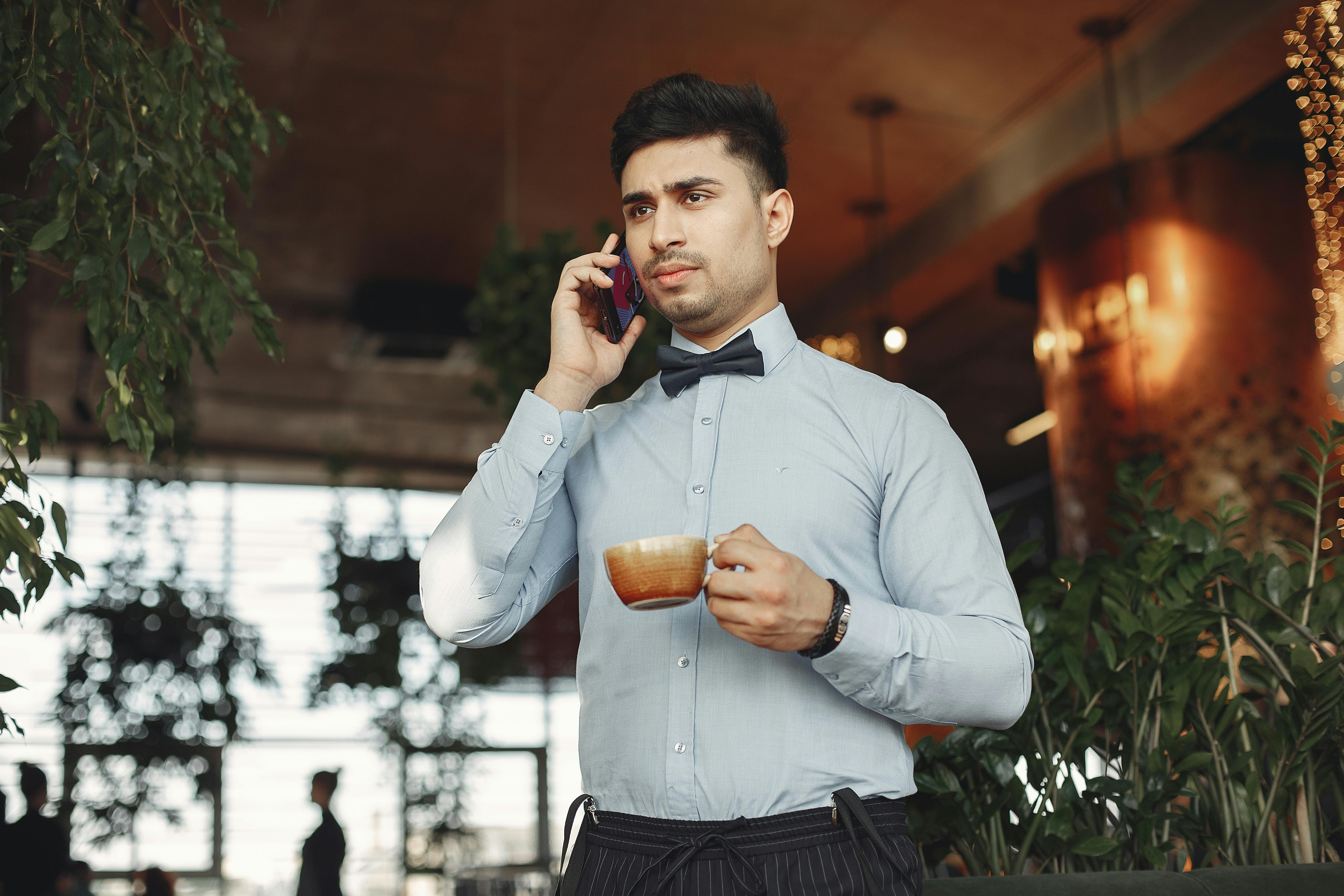 Un hombre de aspecto serio hablando por teléfono mientras sostiene una bebida | Fuente: Pexels