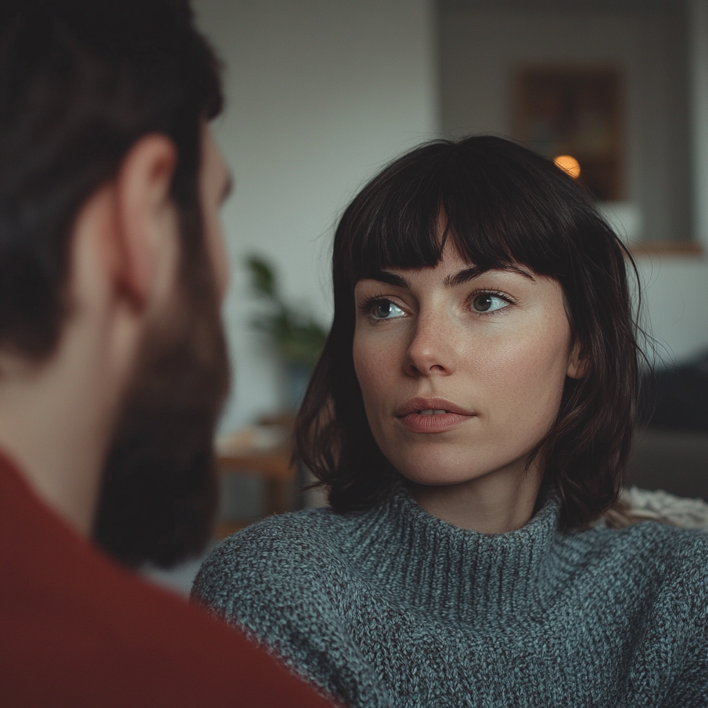 Una mujer seria hablando con un hombre en su salón | Fuente: Midjourney