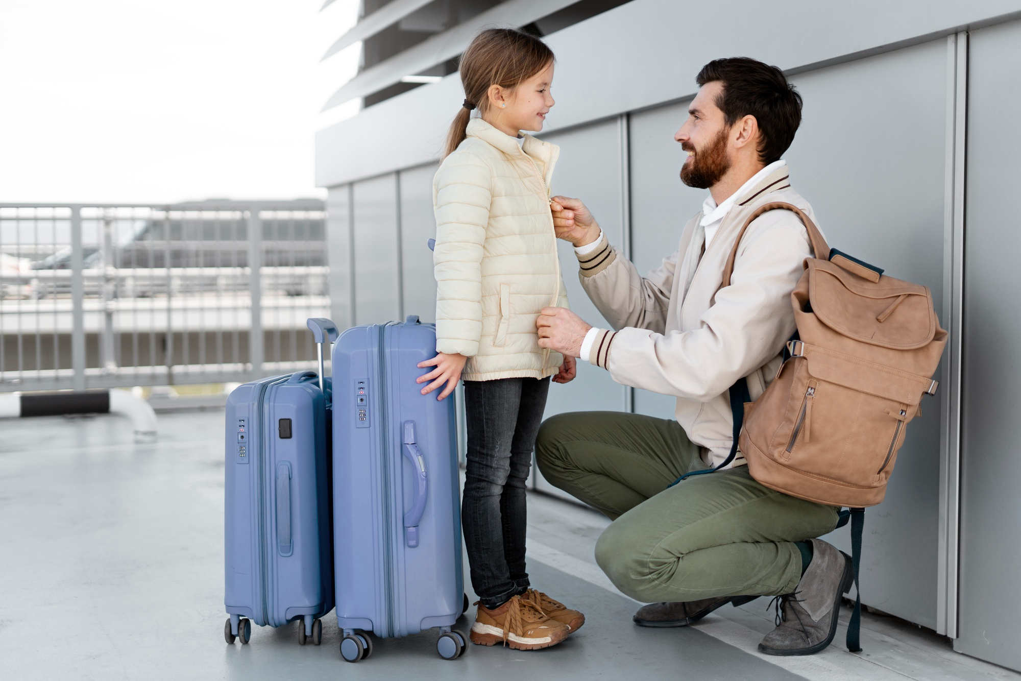 Un padre y su hija listos para su viaje con el equipaje a mano | Fuente: Freepik