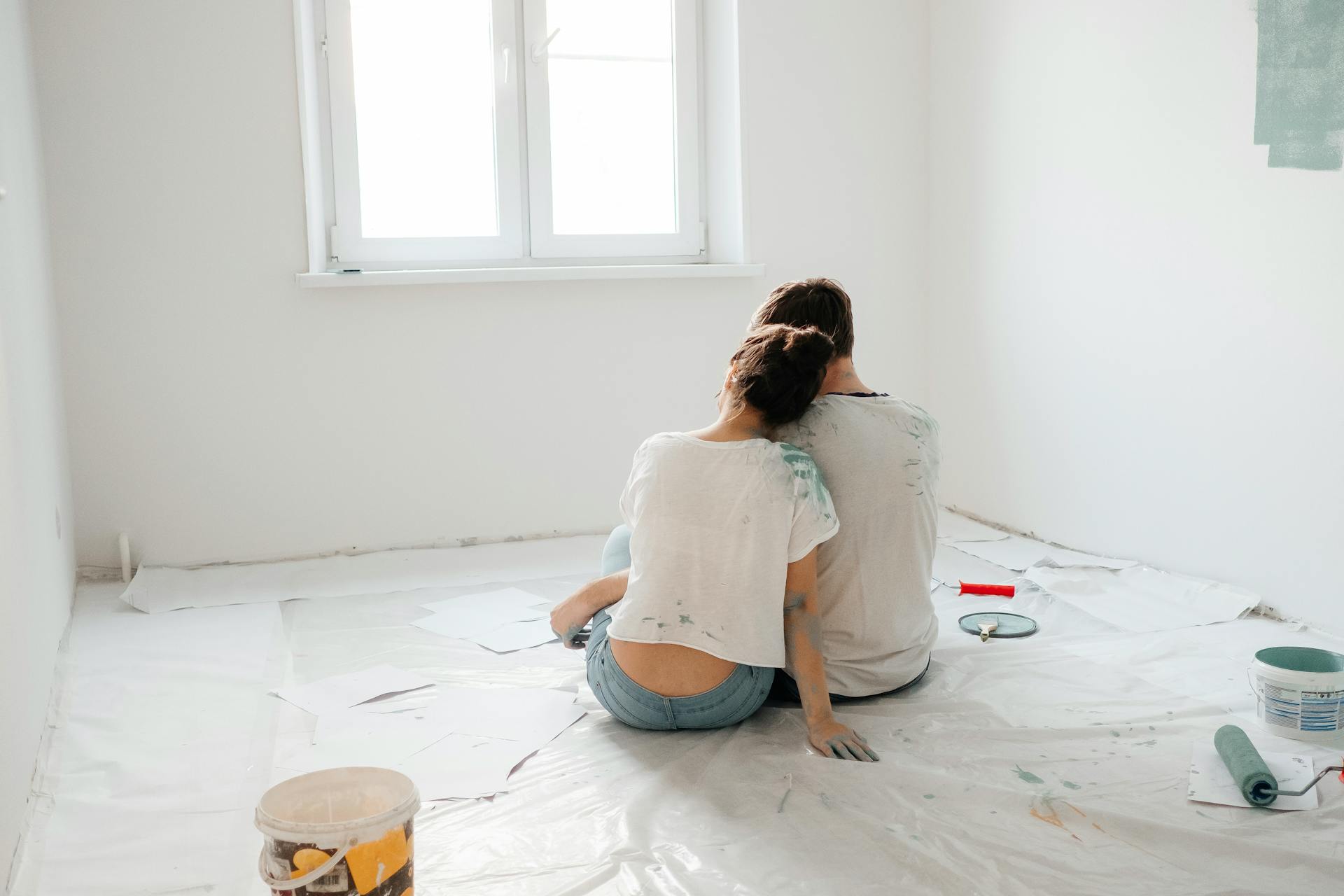 Una pareja tomándose un descanso mientras pinta una habitación | Fuente: Pexels
