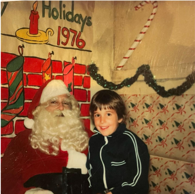 El actor, cuando era un niño, sonríe junto a alguien disfrazado de Papá Noel durante una celebración navideña de 1976, en una foto que plasma un bonito recuerdo de su infancia. | Fuente: Instagram/therealnoahwyle