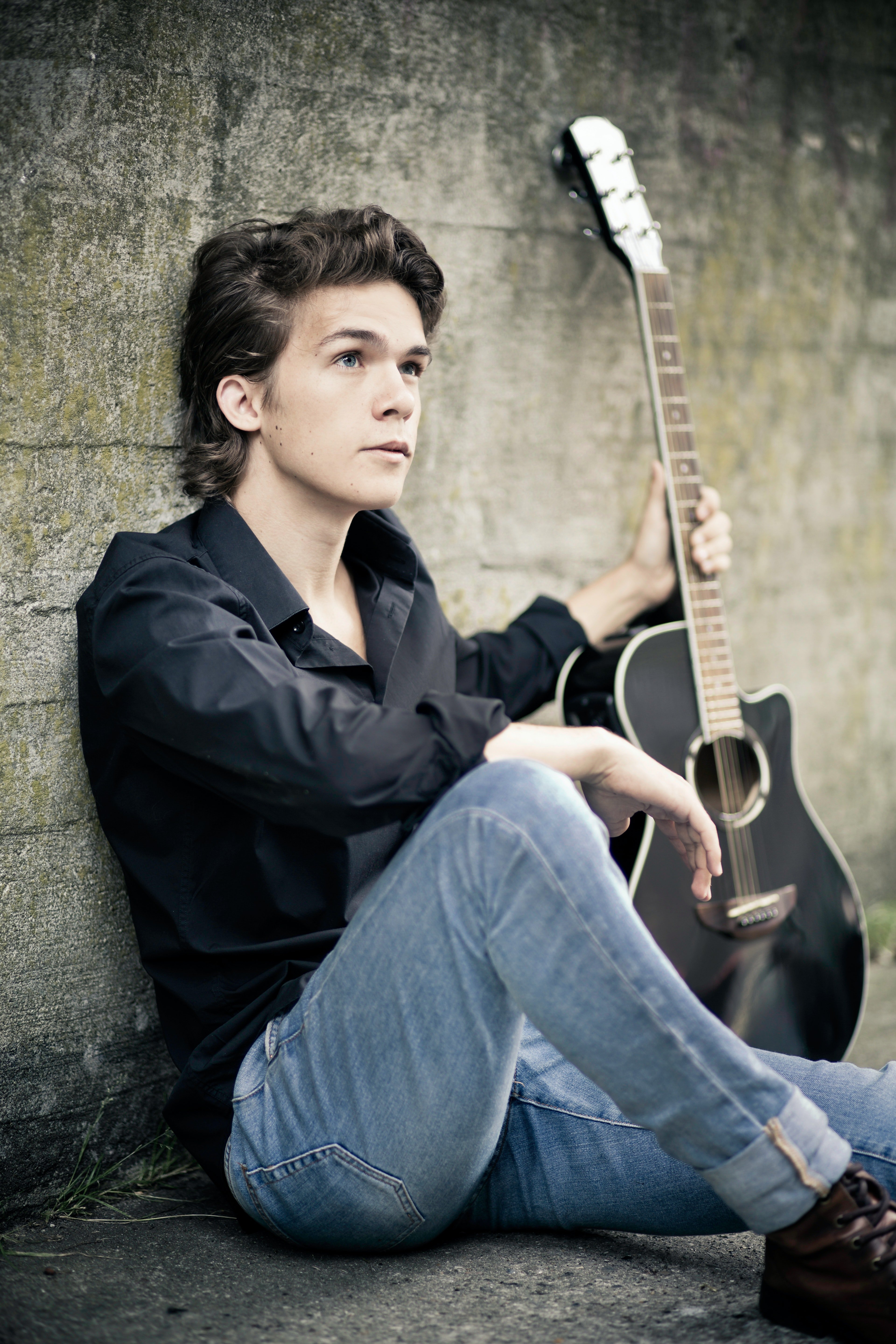 Un joven sentado en el suelo sosteniendo una guitarra. | Foto: Pexels