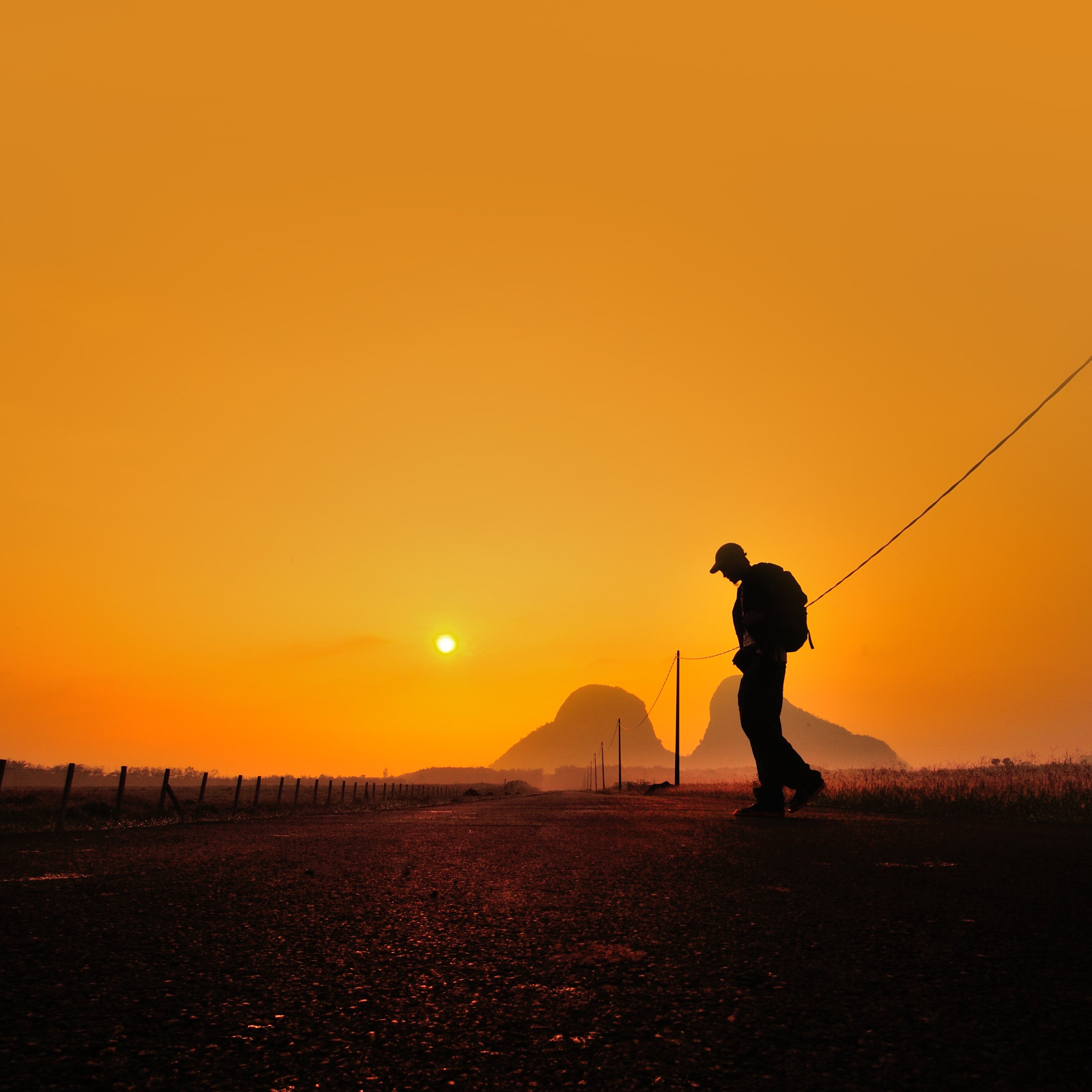 Un hombre con una mochila en su espalda camina al atardecer. | Foto: Shutterstock