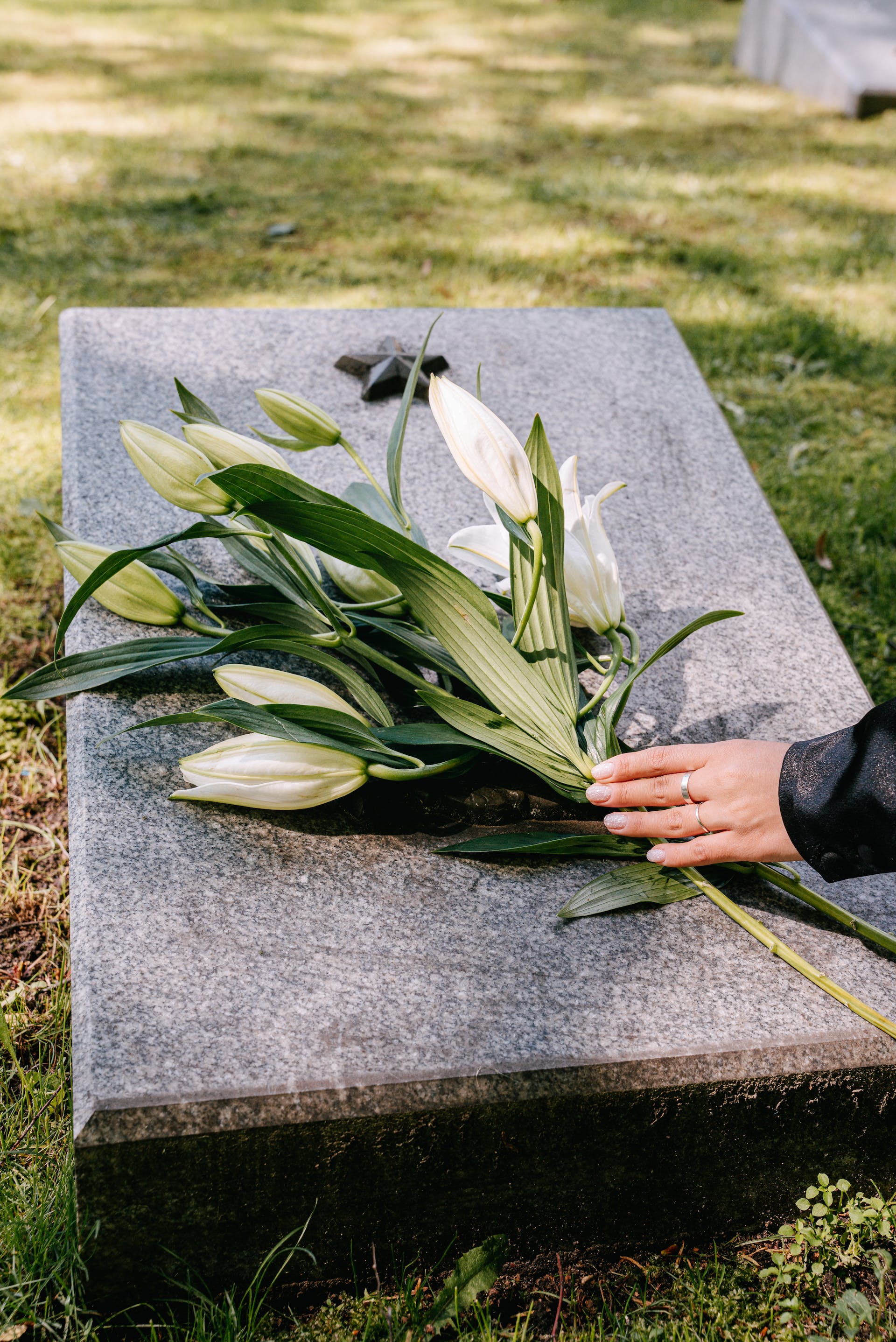 Persona depositando flores en una tumba | Foto: Pexels