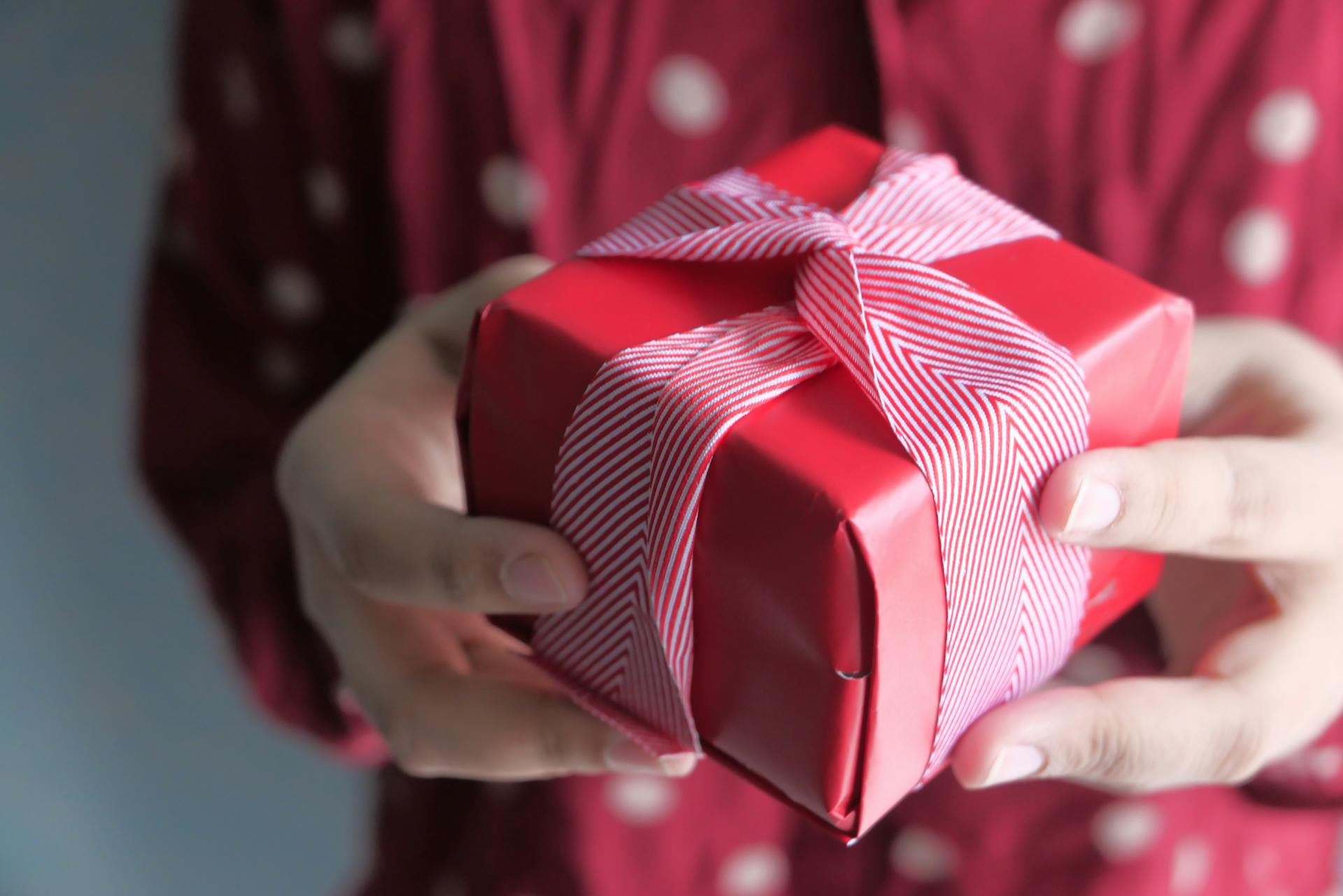 Una mujer sostiene una pequeña caja envuelta para regalo | Fuente: Pexels